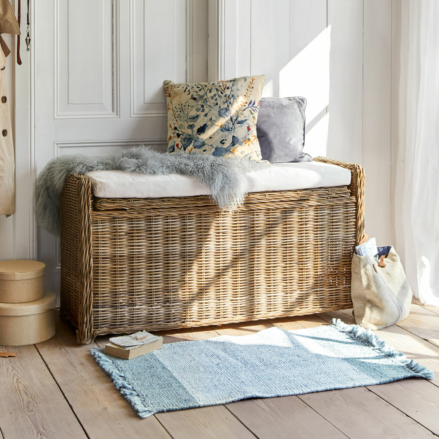 Panca Horton Panca in rattan colore naturale con cuscino bianco e cuscini decorativi in ambiente luminoso