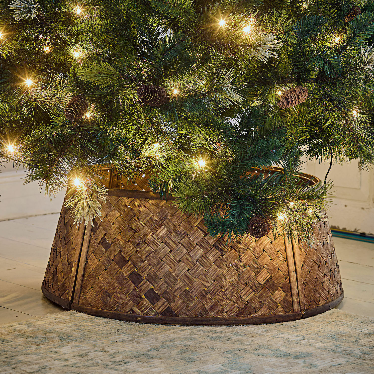 Copertura per la base dell’albero di Natale Eden Supporto per albero di Natale in legno intrecciato marrone sotto albero verde con luci e pigne