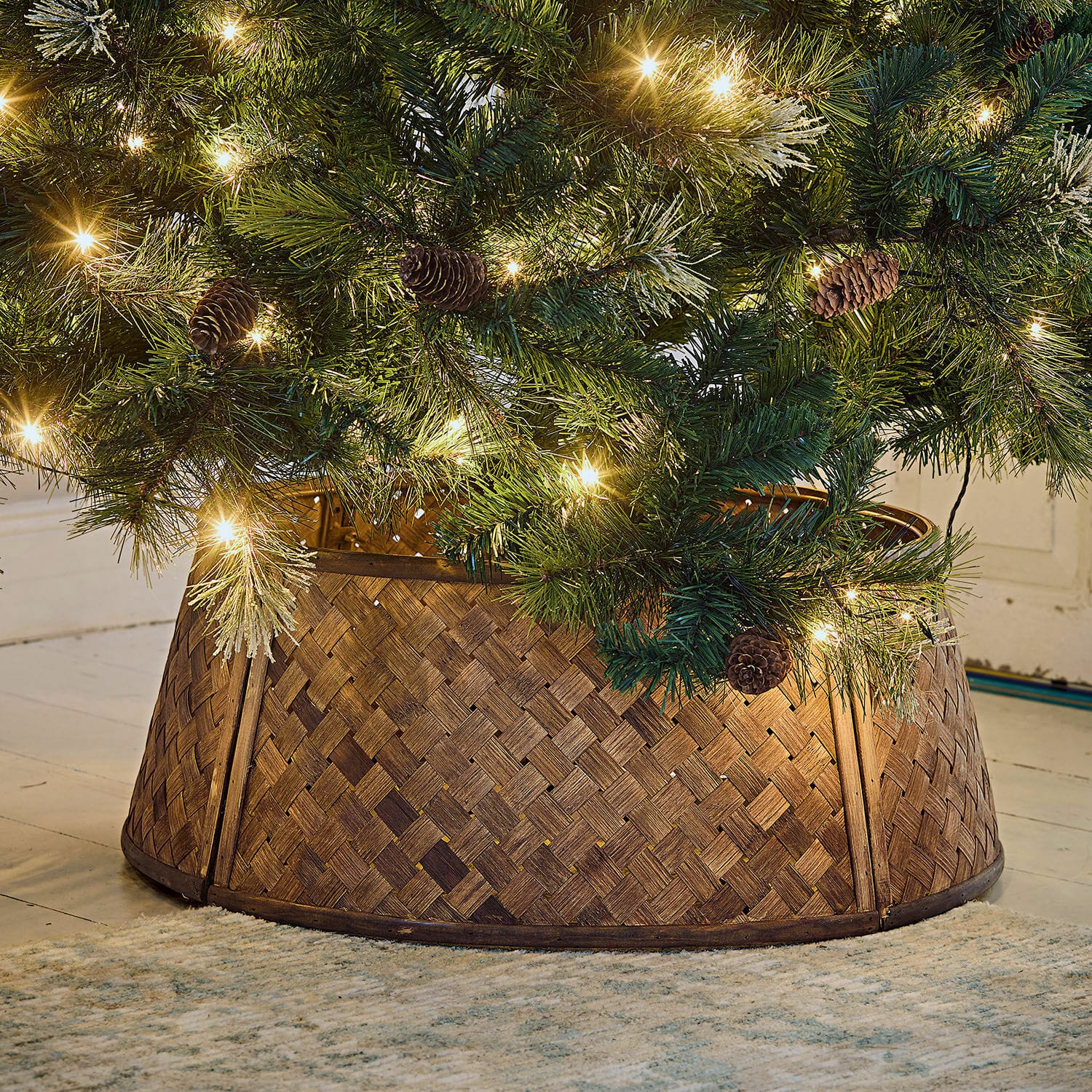 Copertura per la base dell’albero di Natale Eden Supporto per albero di Natale in legno intrecciato marrone sotto albero verde con luci e pigne