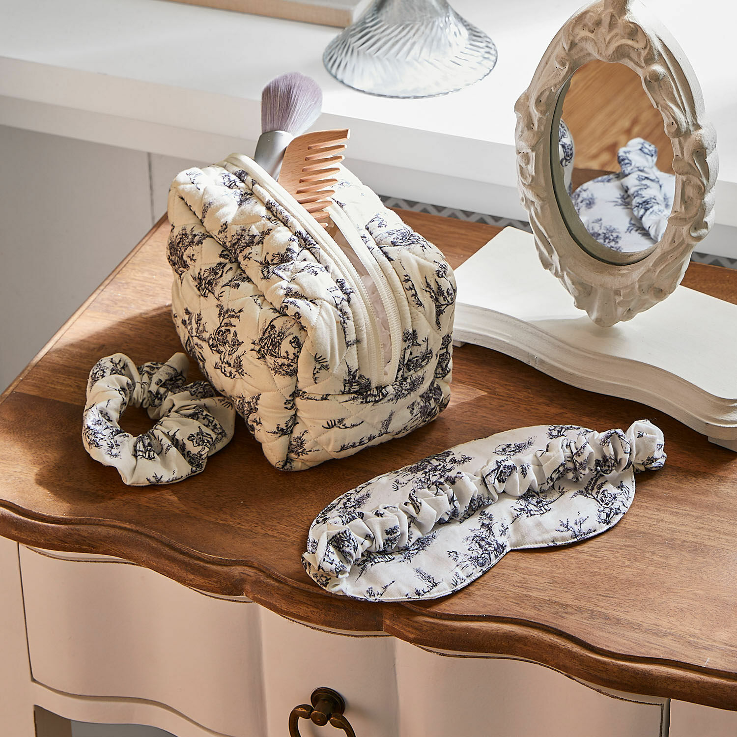 Set di 3 accessori da notte Felencio Beauty case trapuntato beige con motivo nero, fascia e mascherina per dormire su tavolo in legno, accessori per la cura