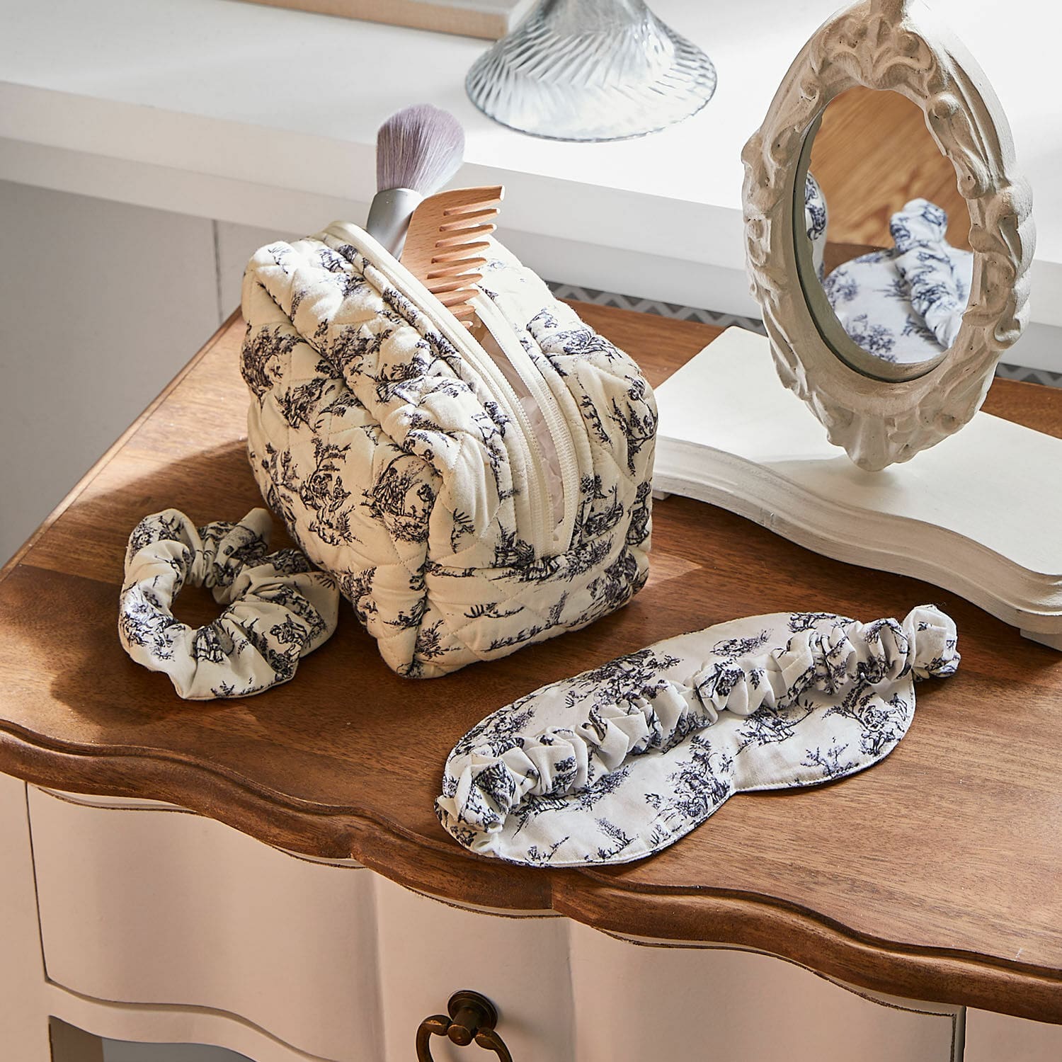 Set di 3 accessori da notte Felencio Beauty case trapuntato beige con motivo nero, fascia e mascherina per dormire su tavolo in legno, accessori per la cura