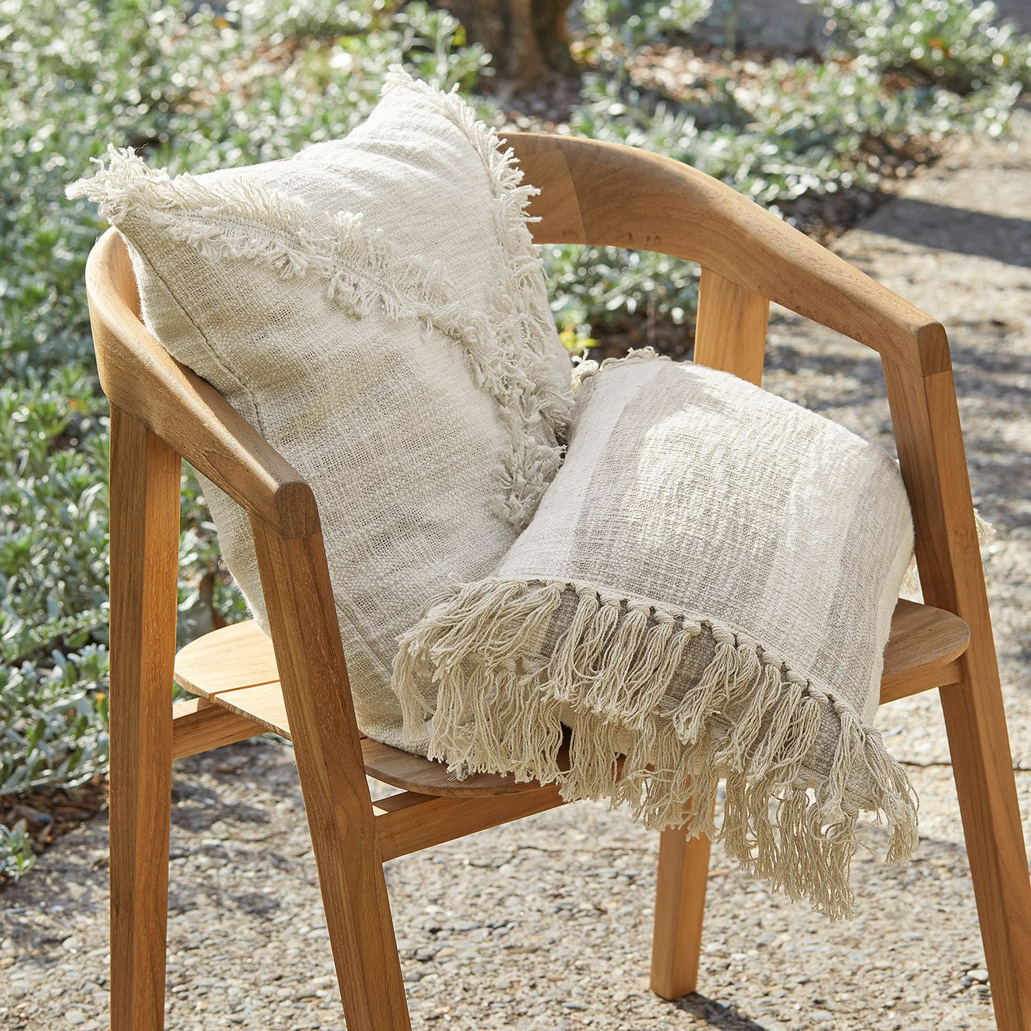 Coppia di copricuscini Freya Cuscino beige in cotone e coperta con frange su sedia in legno da giardino