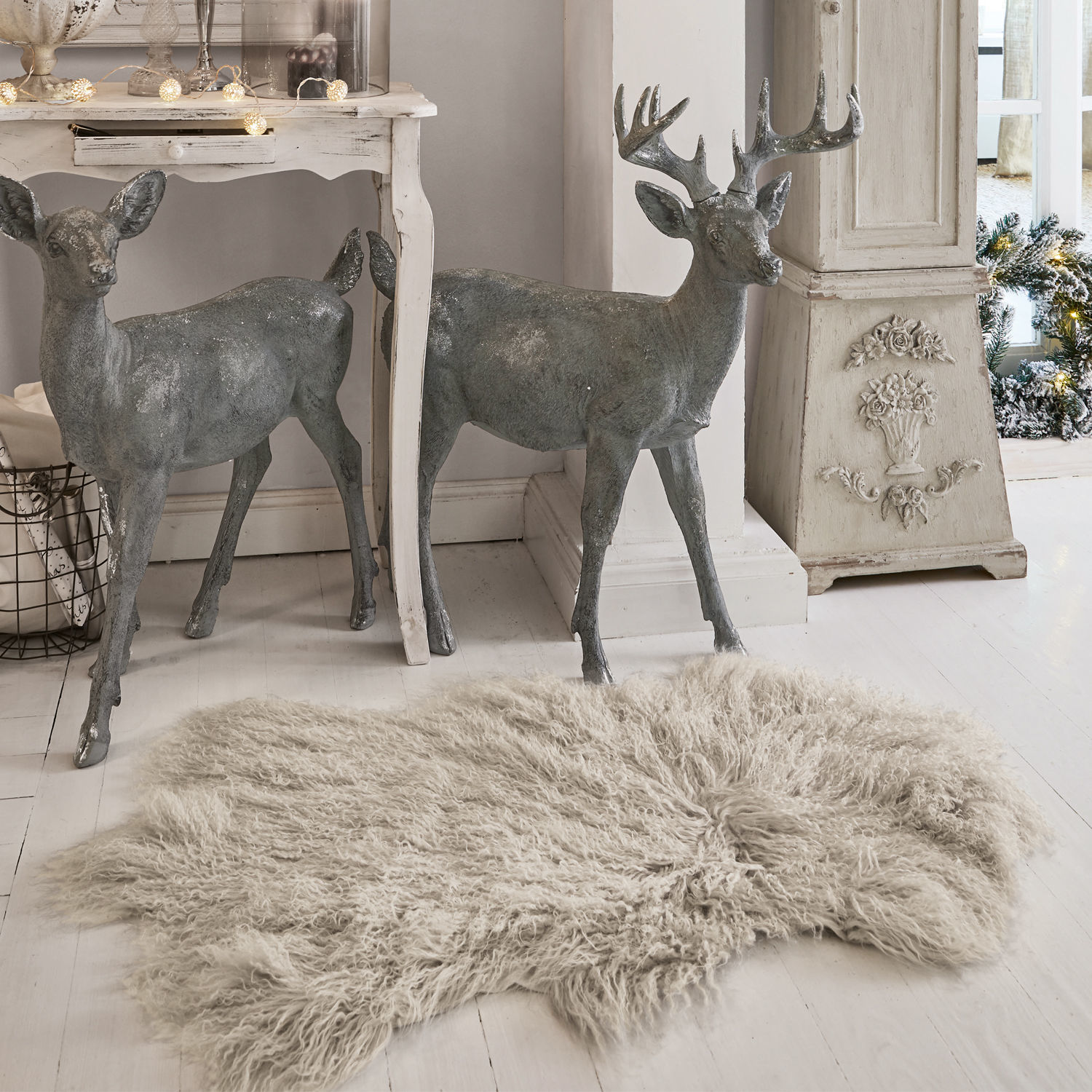 Vello di agnello Gad Figure decorative di cervi grigie in metallo accanto a tavolo bianco e tappeto beige a pelo lungo