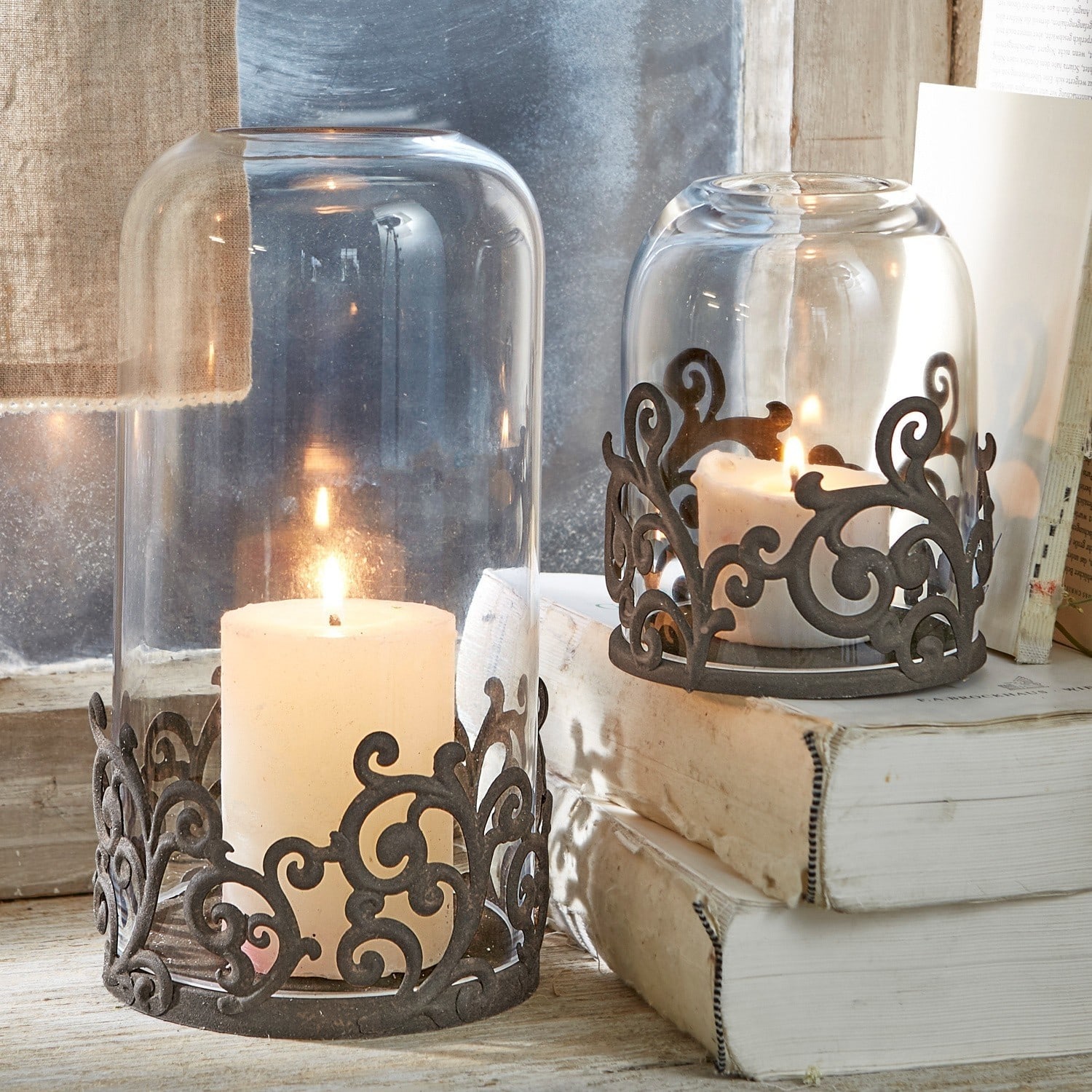 Coppia di portacandele Mala Lanterna in vetro con base in metallo nero decorativo e candele bianche su tavolo in legno