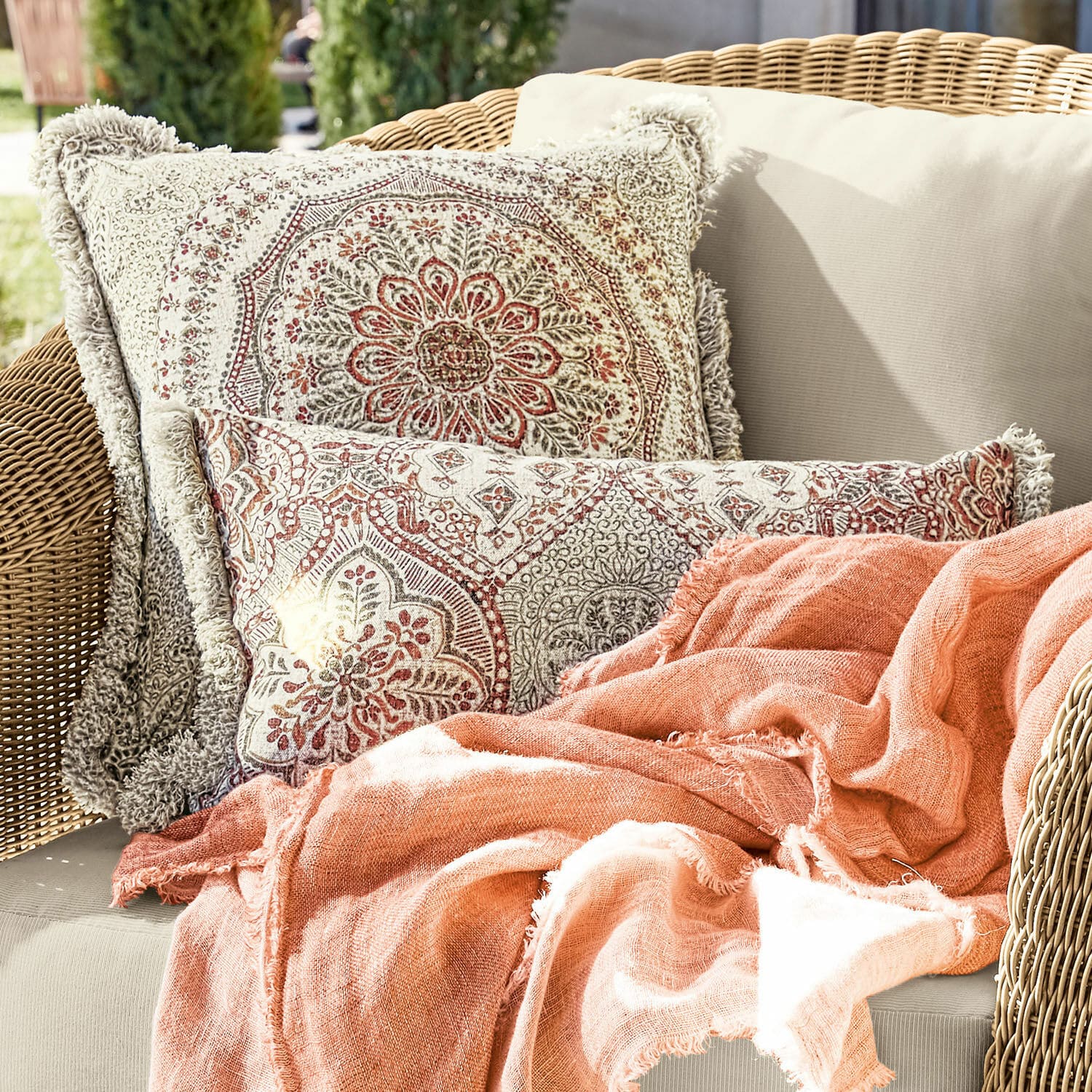 Coppia di copricuscini Margret Cuscini decorativi in cotone beige e rosso a doppia faccia con coperta arancione su divano in vimini