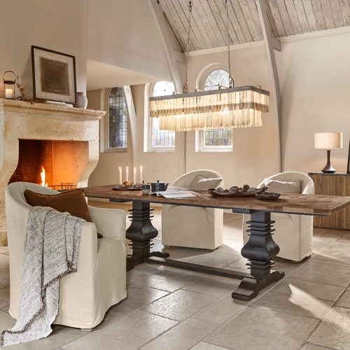 Sala da pranzo con tavolo in legno e poltrone crema vicino al camino, stile rustico accogliente