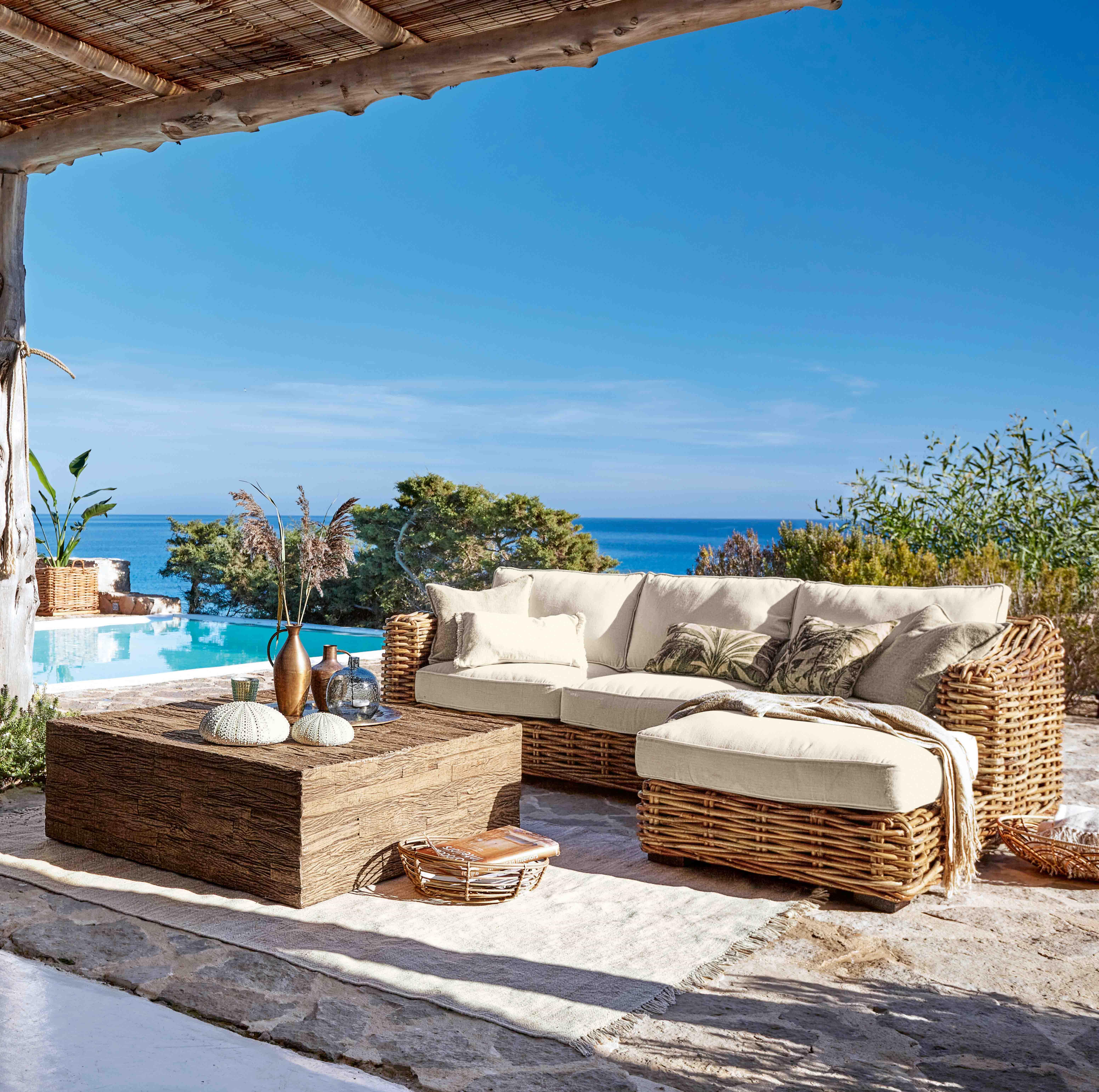 Set di mobili da giardino in rattan con cuscini crema, vista piscina e mare, area esterna