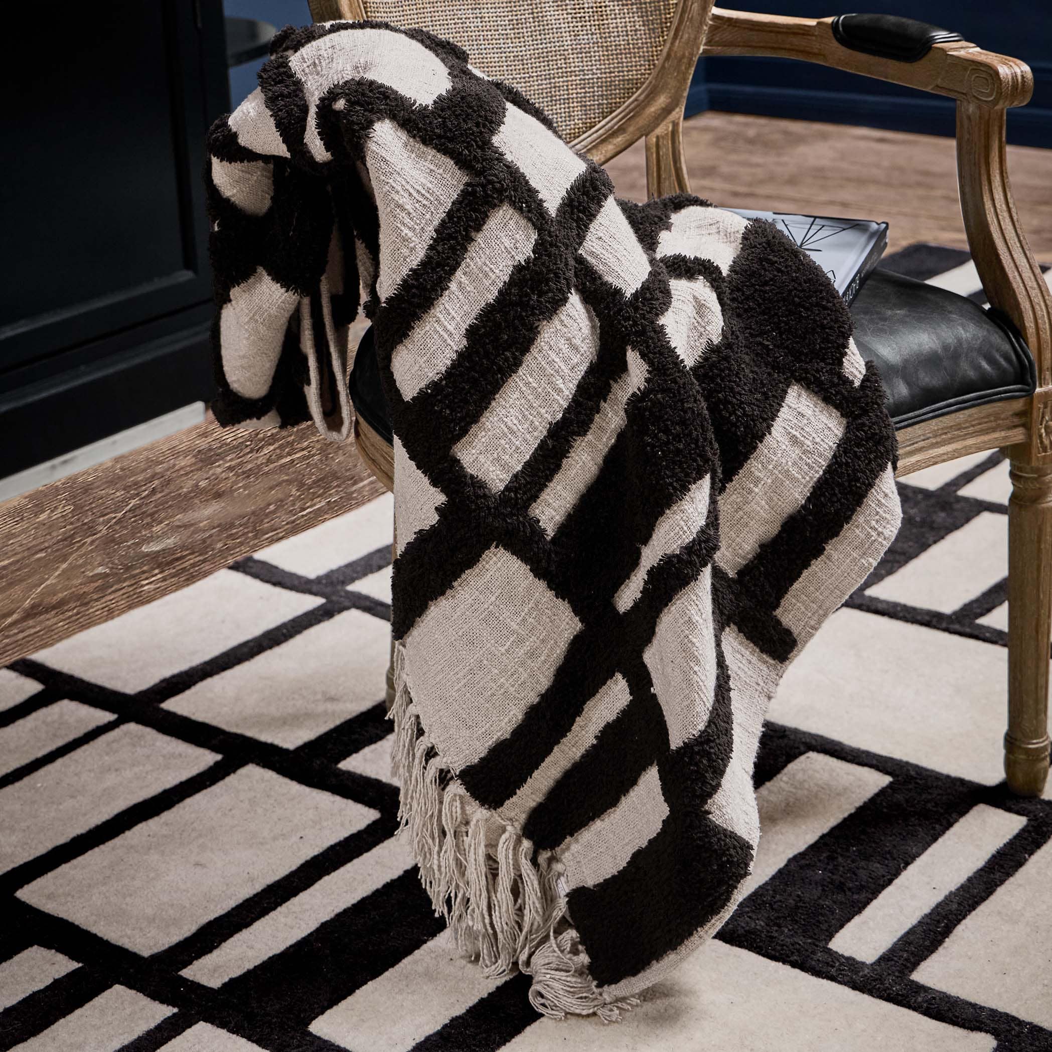 Plaid bianco e nero con motivo geometrico in tessuto morbido su sedia in legno in soggiorno