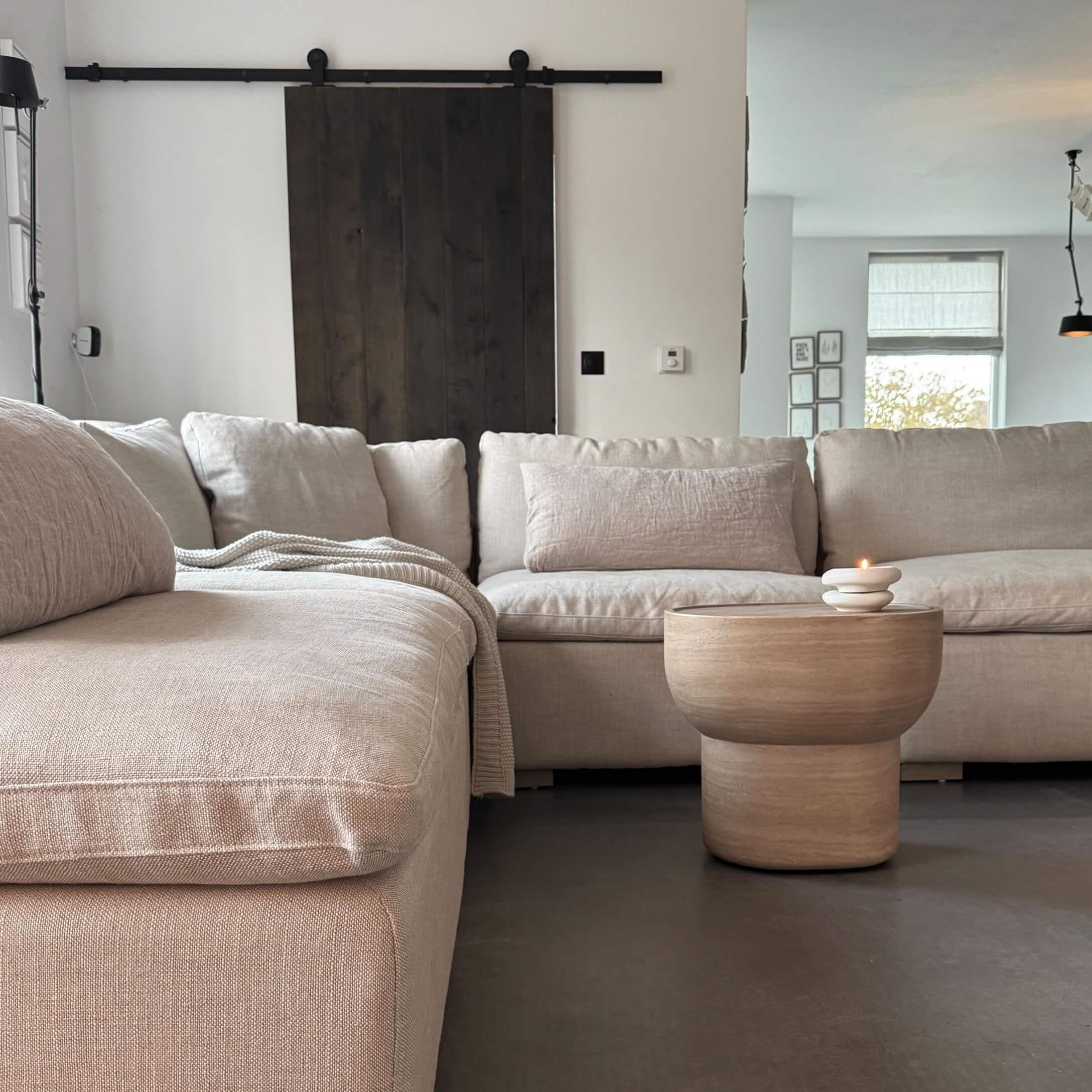 Divano angolare beige in tessuto con tavolino in legno e candela in soggiorno moderno