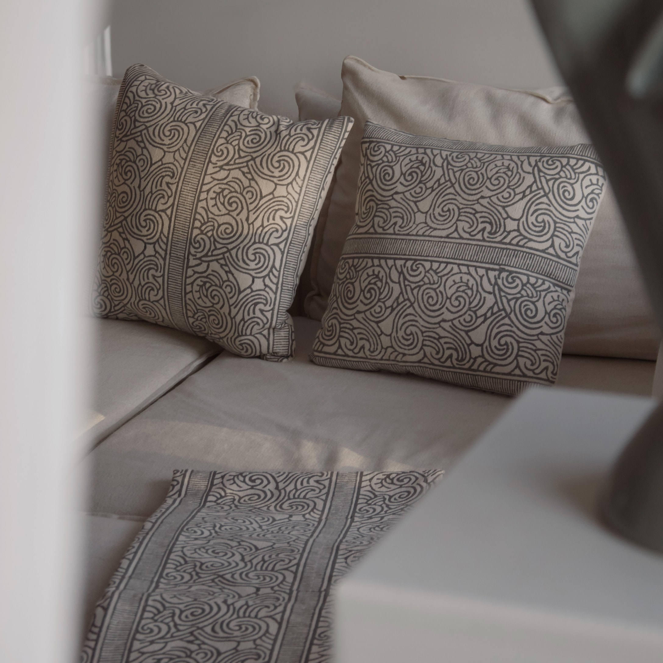 Cuscini beige con motivo grigio decorativo su divano chiaro, tessuti per il soggiorno