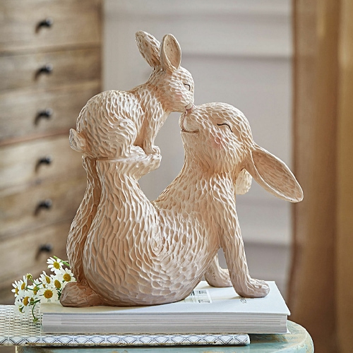 Figura in ceramica beige di due conigli abbracciati su libri, decorazione primaverile delicata