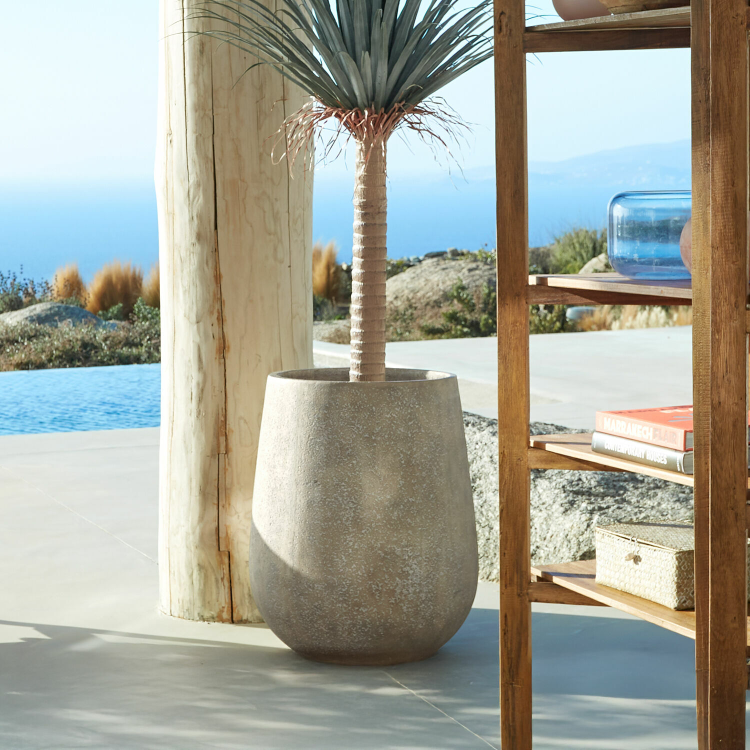 Portavaso Bressac Grande vaso in cemento grigio con pianta decorativa su terrazza con vista mare