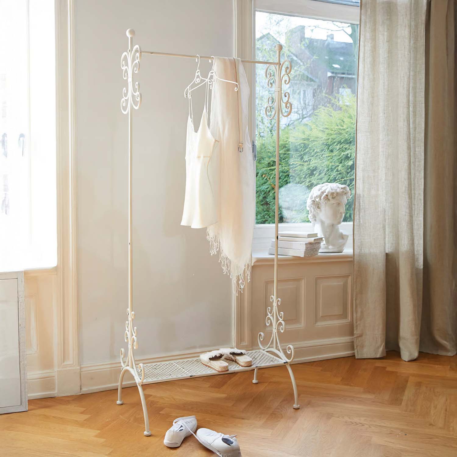 Appendiabiti in metallo bianco con dettagli decorativi in stanza luminosa con pavimento in legno