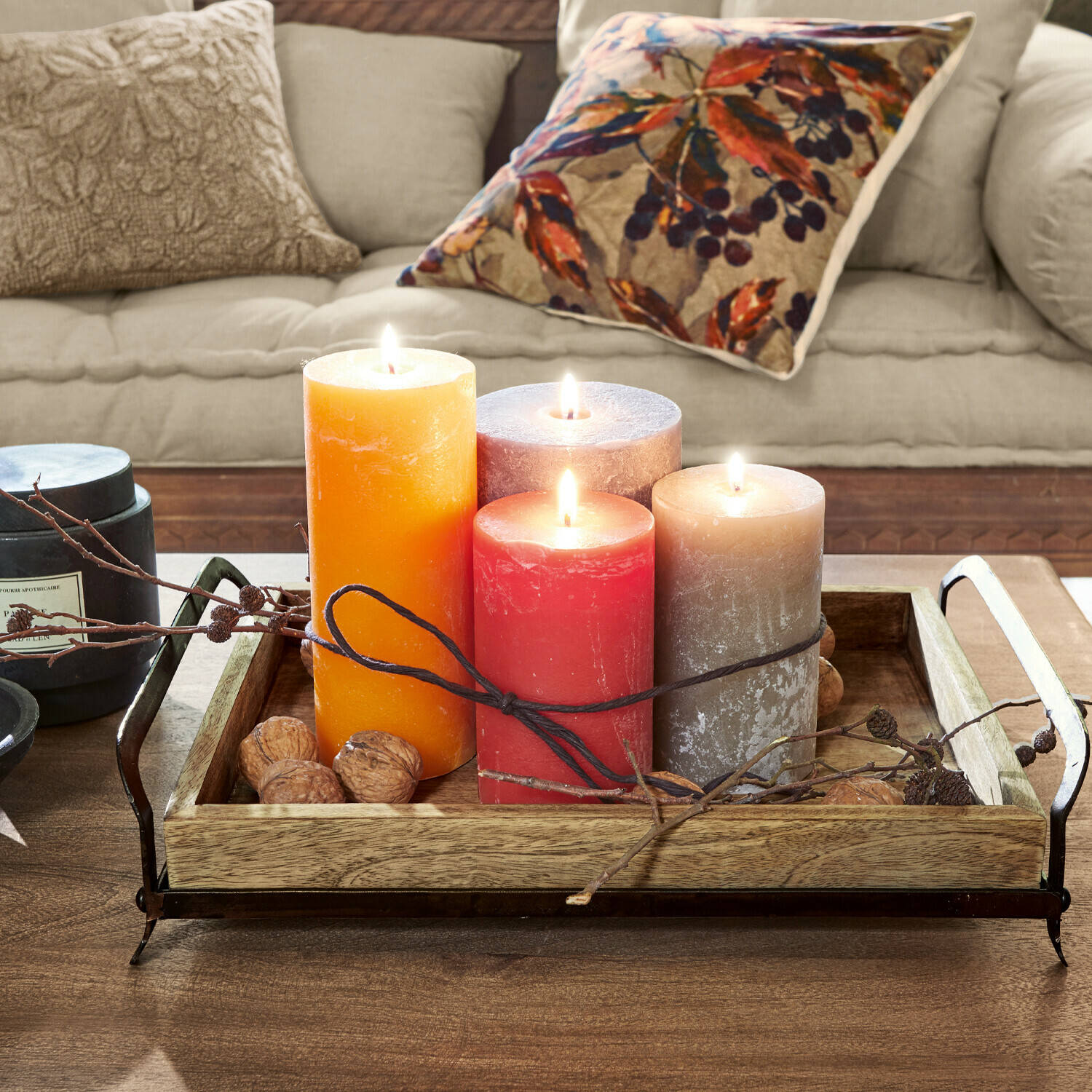 Set di 4 candele Joliet Quattro candele colorate su un vassoio in legno con manici in metallo su un tavolo in legno