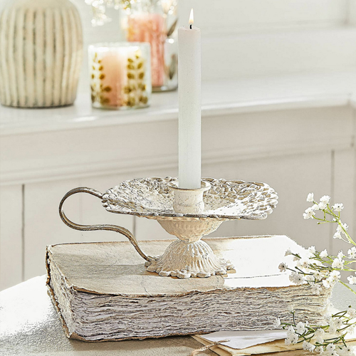 Portacandele in metallo color crema stile vintage su libro bianco, decorazione da tavolo con fiori bianchi