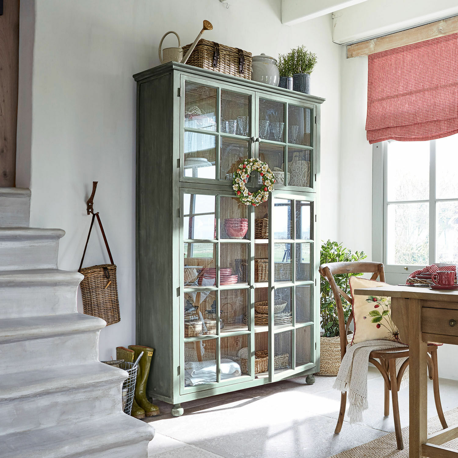 Mobile alto Bellac Vetrina in legno verde con ante in vetro in soggiorno luminoso con decorazioni naturali