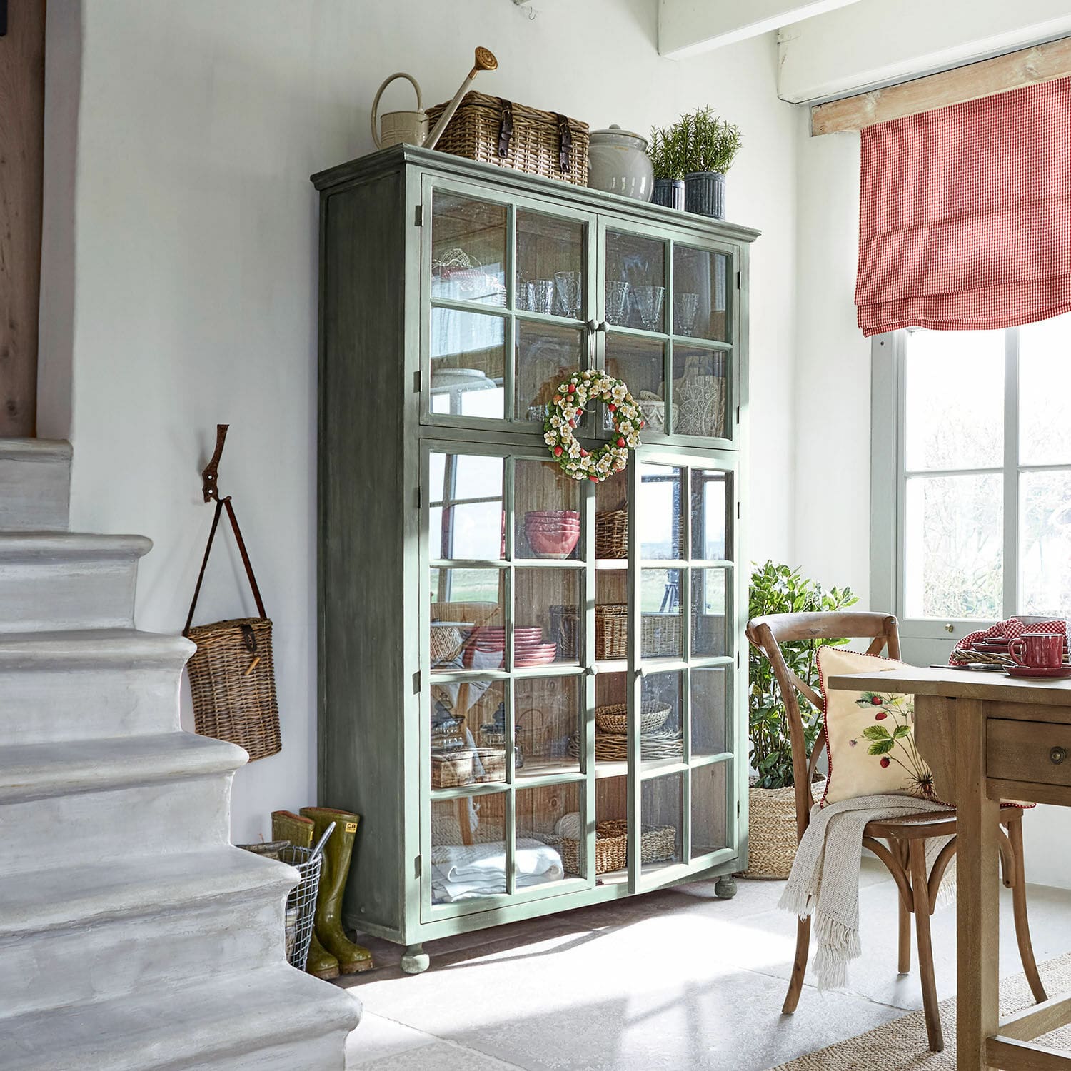 Mobile alto Bellac Vetrina in legno verde con ante in vetro in soggiorno luminoso con decorazioni naturali