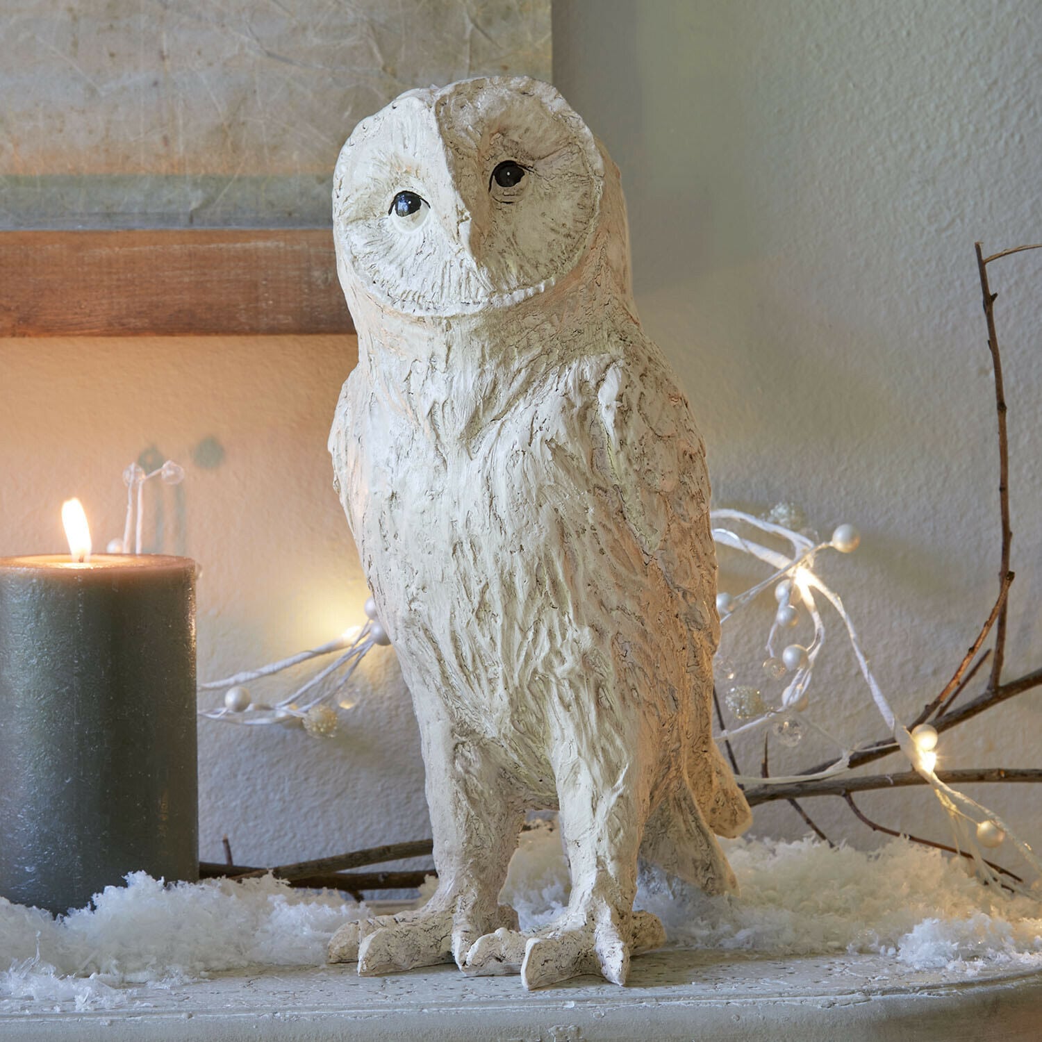 Civetta decorativa Heriette Figura decorativa di gufo in materiale chiaro su tavolo festivo con candela e luci decorative