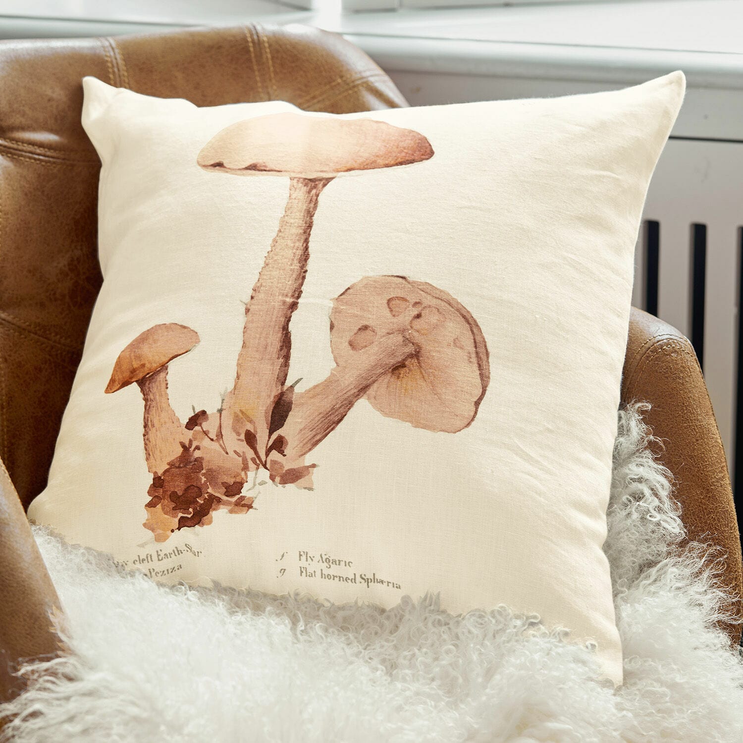 Copricuscino Laval Cuscino in lino beige con stampa di funghi marroni su poltrona in pelle marrone