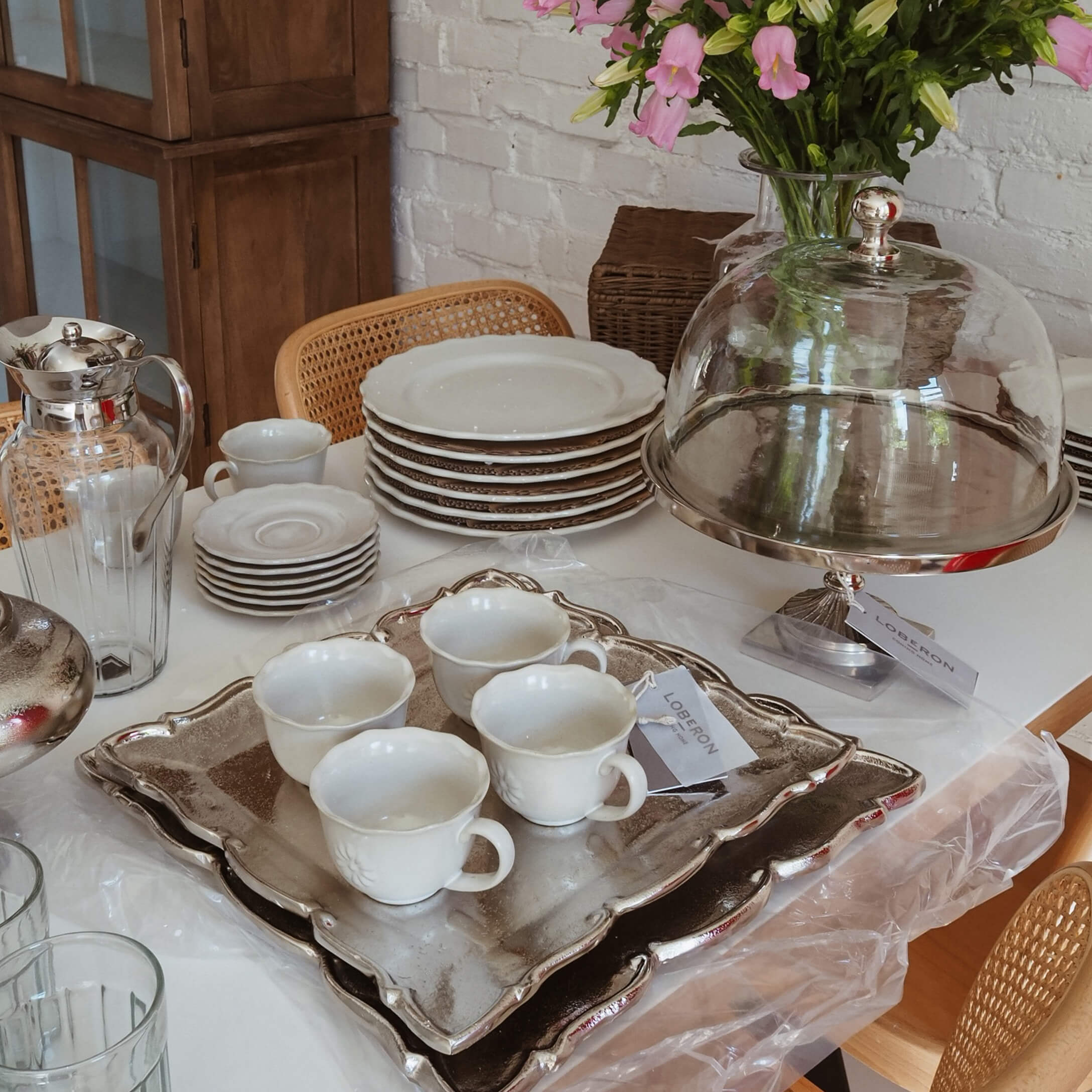 Servizio in porcellana bianca con tazze e piatti su vassoio argentato, decorazione tavola slow living