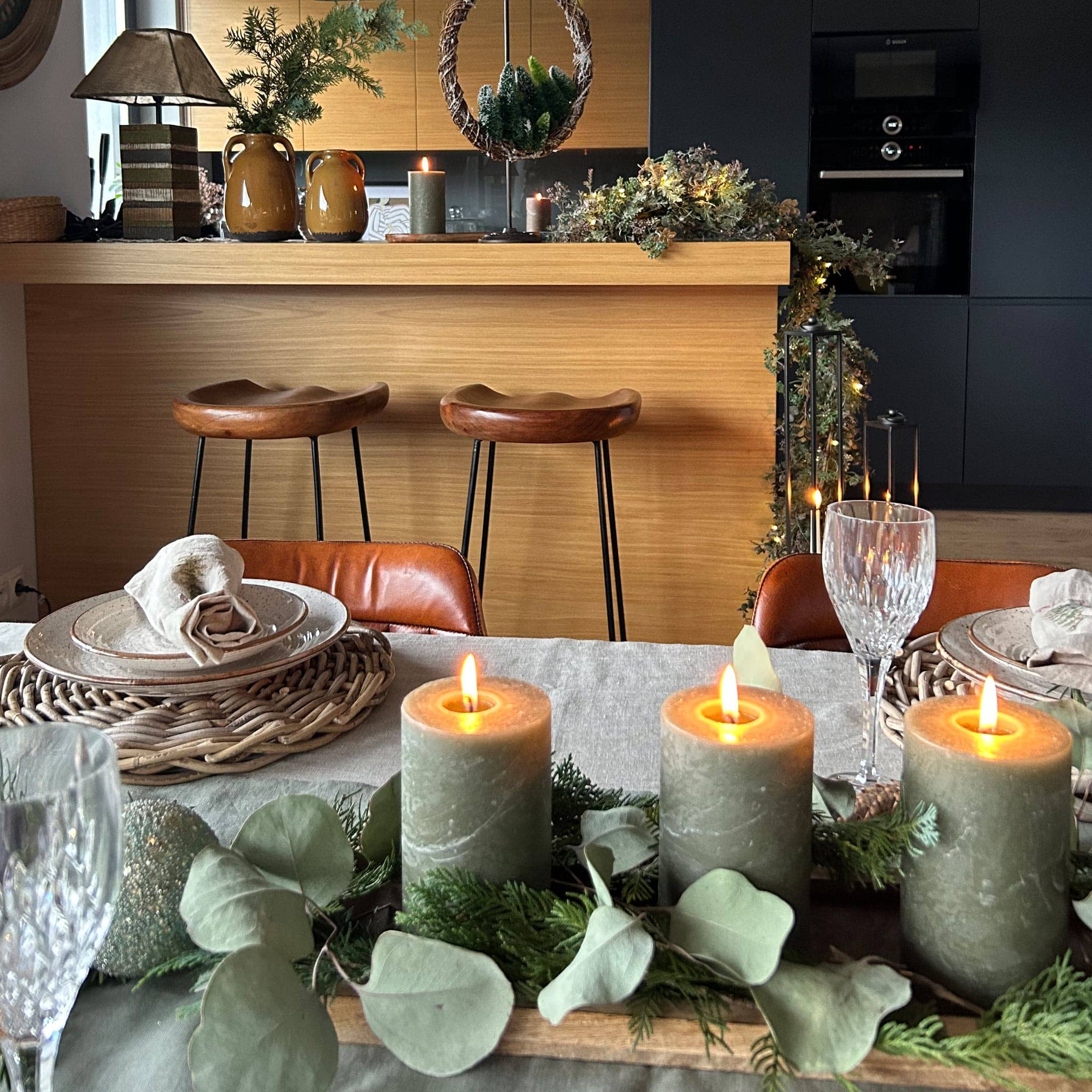 Candele decorative verdi con foglie naturali su vassoio in legno su tavola da pranzo elegante