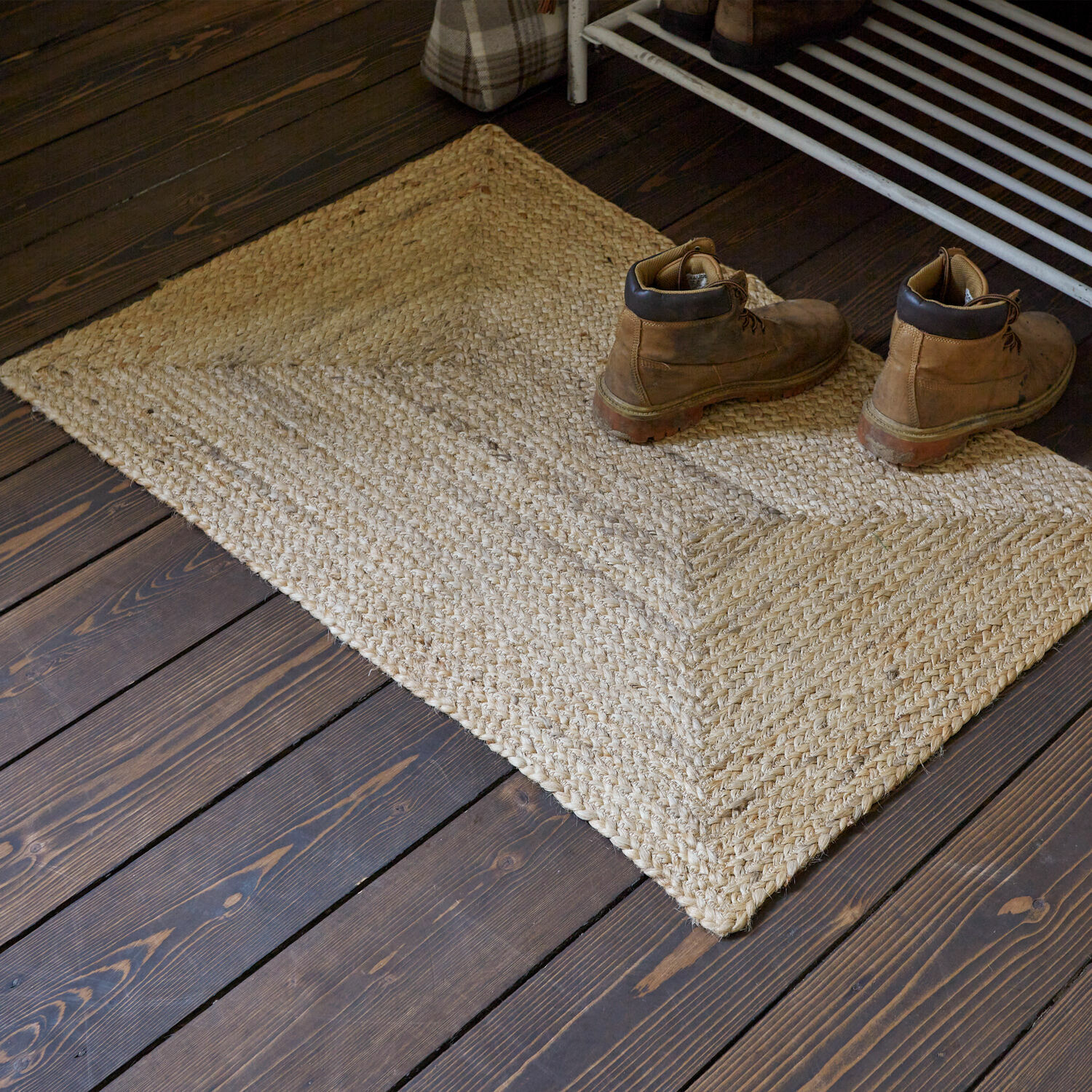 Passatoia Révalaine Tappeto beige in juta su pavimento in legno scuro con paio di stivali in pelle marrone