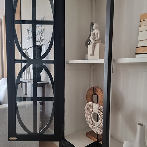 Vetrina in metallo nero con mensole decorative e sculture in soggiorno luminoso