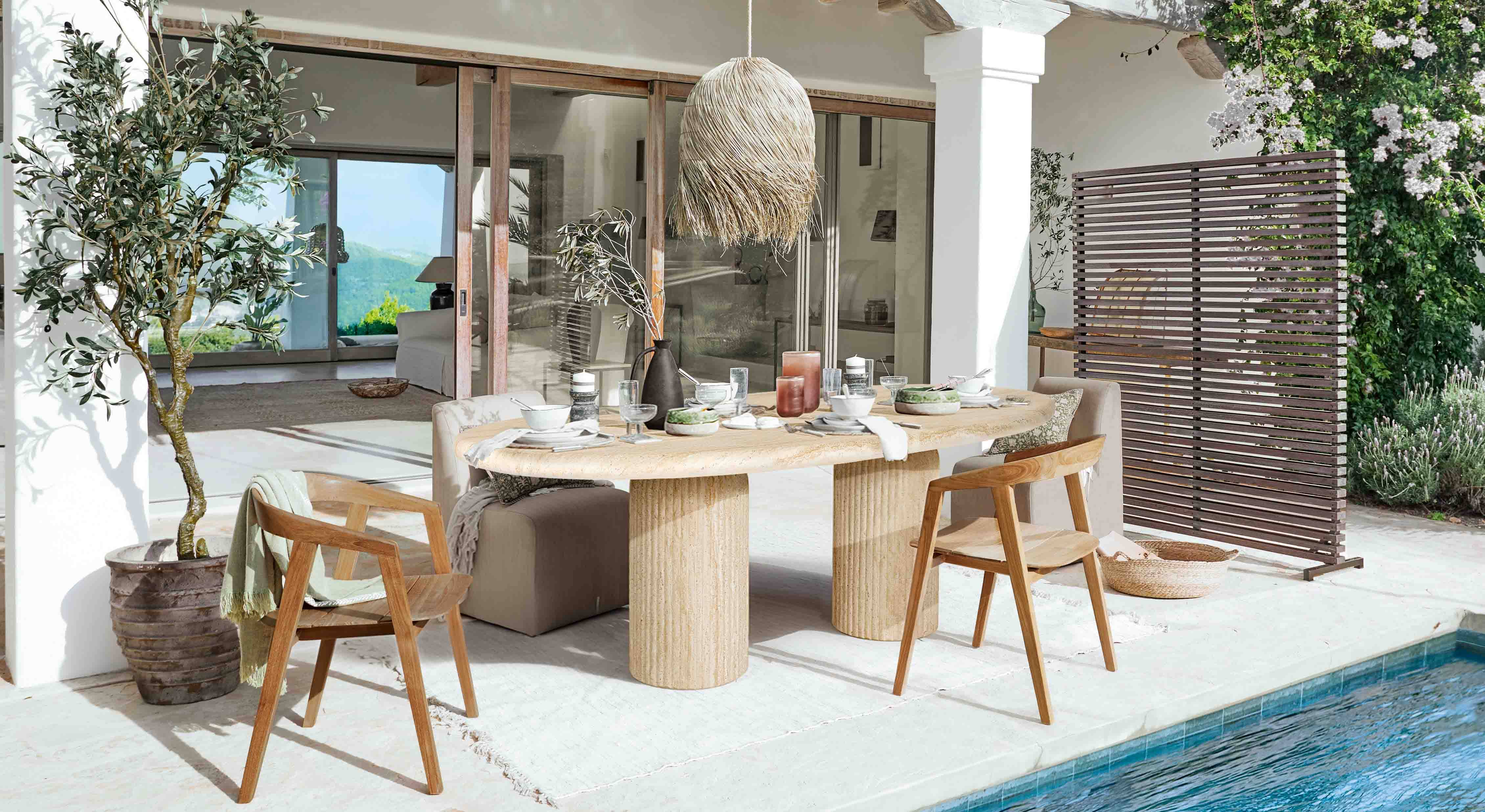 Zona pranzo esterna con tavolo in pietra e sedie in legno vicino alla piscina in stile naturale