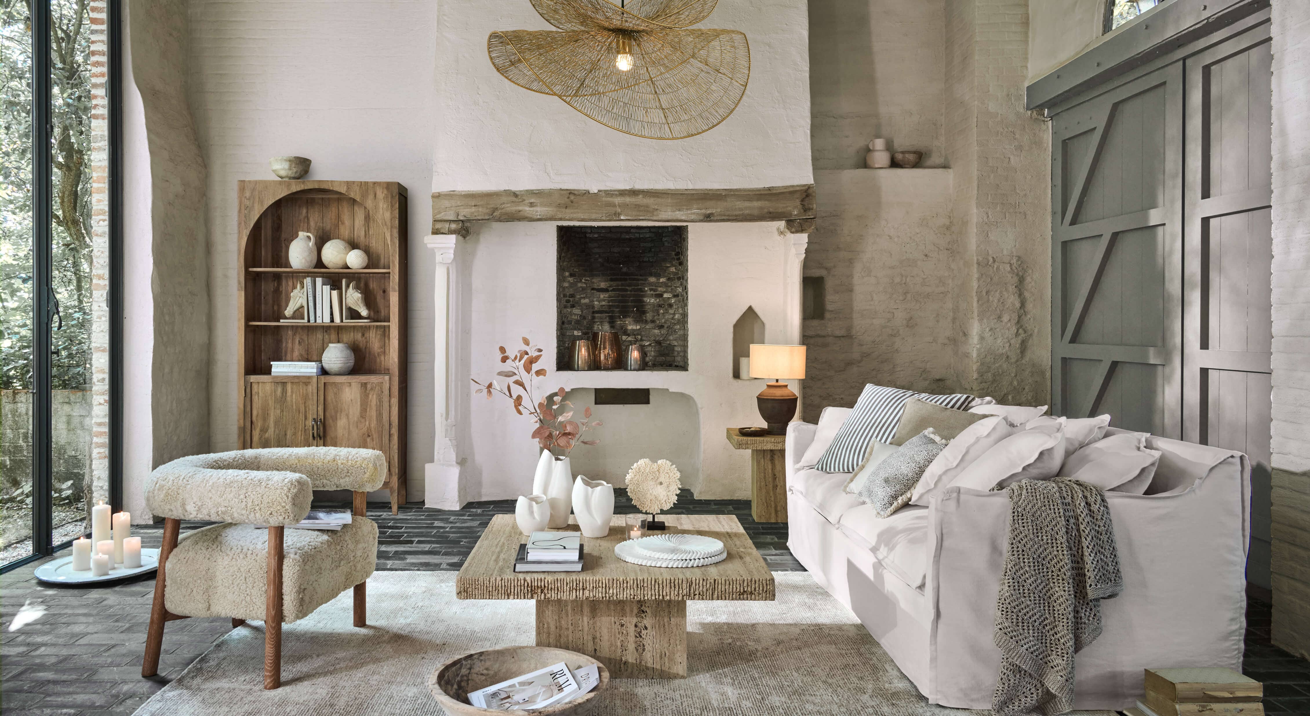 Soggiorno accogliente con divano bianco, poltrona beige in tessuto e tavolino in legno su tappeto chiaro