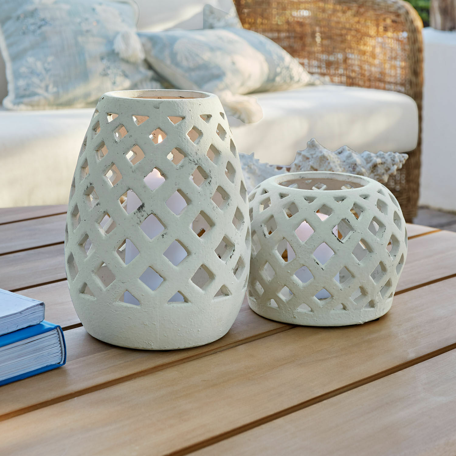 Coppia di lanterne Serignac Due lanterne in ceramica bianca con motivo traforato su tavolo in legno in soggiorno