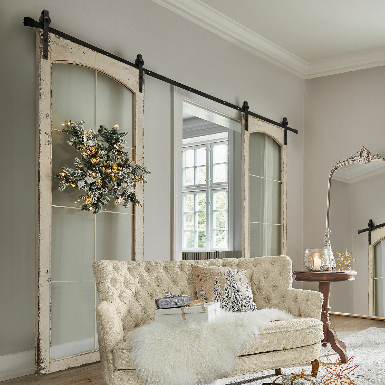 Porta scorrevole a doppia anta Incles Divano beige trapuntato con coperta di pelliccia sintetica e decorazioni natalizie in soggiorno luminoso con porte scorrevoli