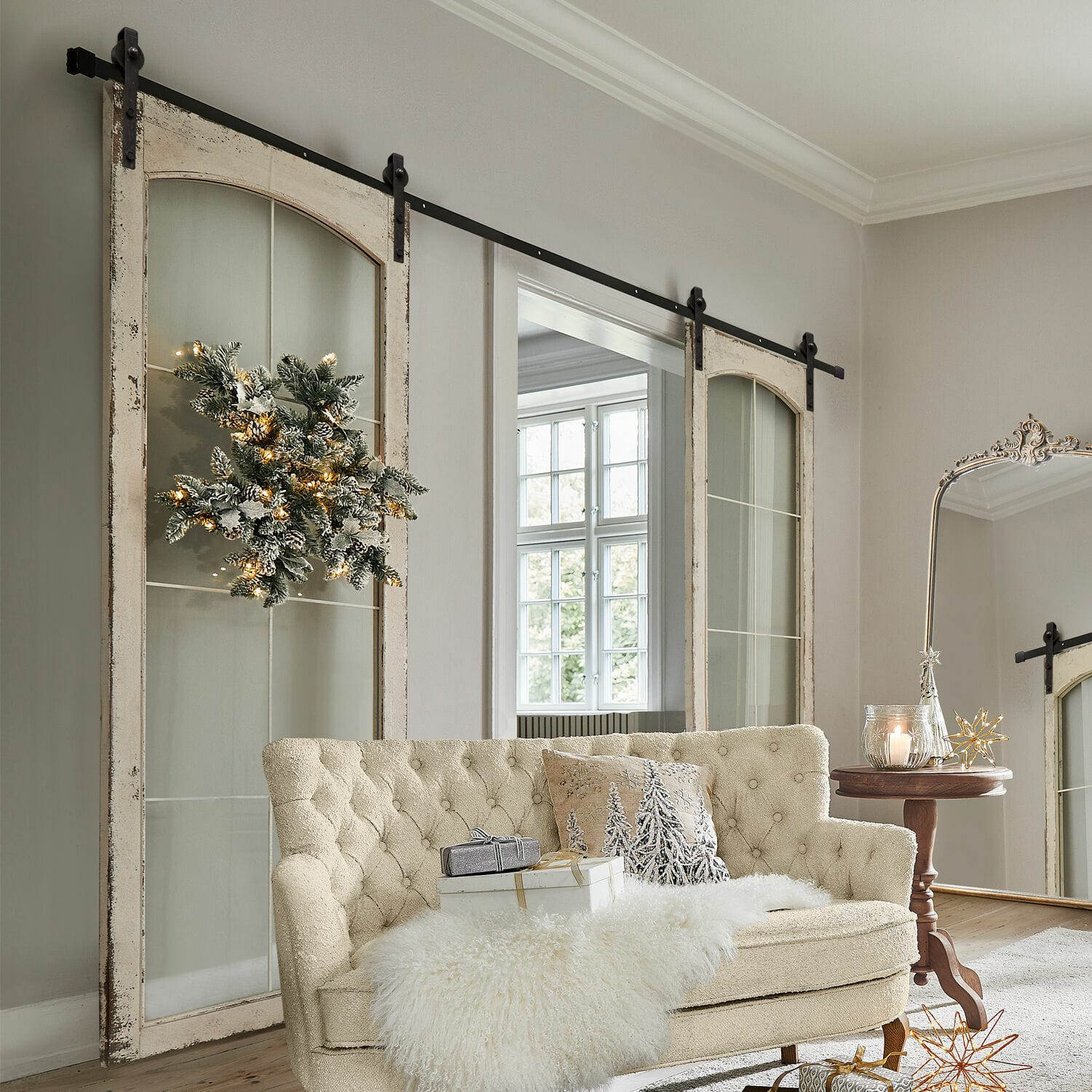 Porta scorrevole a doppia anta Incles Divano beige trapuntato con coperta di pelliccia sintetica e decorazioni natalizie in soggiorno luminoso con porte scorrevoli