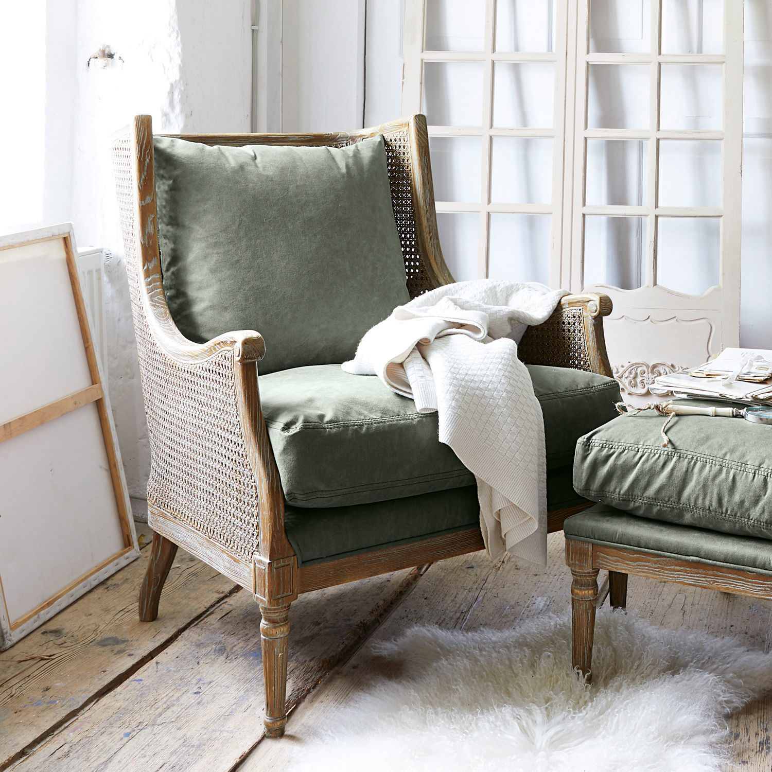 Poltrona Greenbrier Poltrona con struttura in legno e rivestimento verde in tessuto, coperta bianca su tappeto di pelliccia chiara