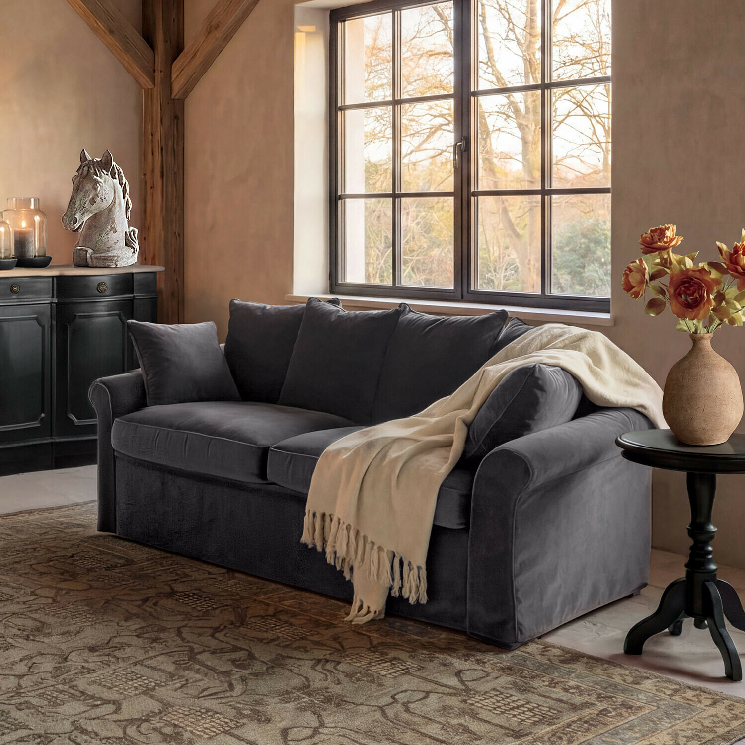 Divano Long Beach Divano in velluto grigio con coperta crema in soggiorno accogliente con decorazione testa di cavallo e fiori