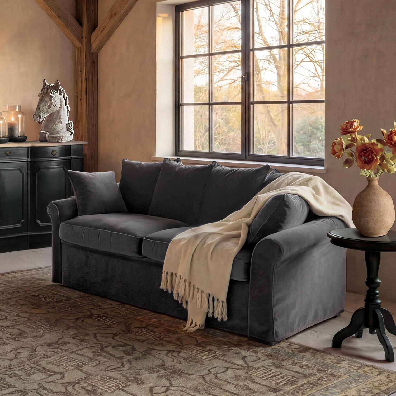 Divano Long Beach Divano in velluto grigio con coperta crema in soggiorno accogliente con decorazione testa di cavallo e fiori