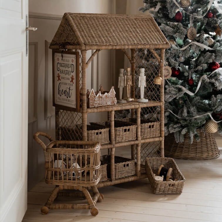 Mobili in rattan naturale con cesti e decorazioni natalizie accanto ad albero decorato