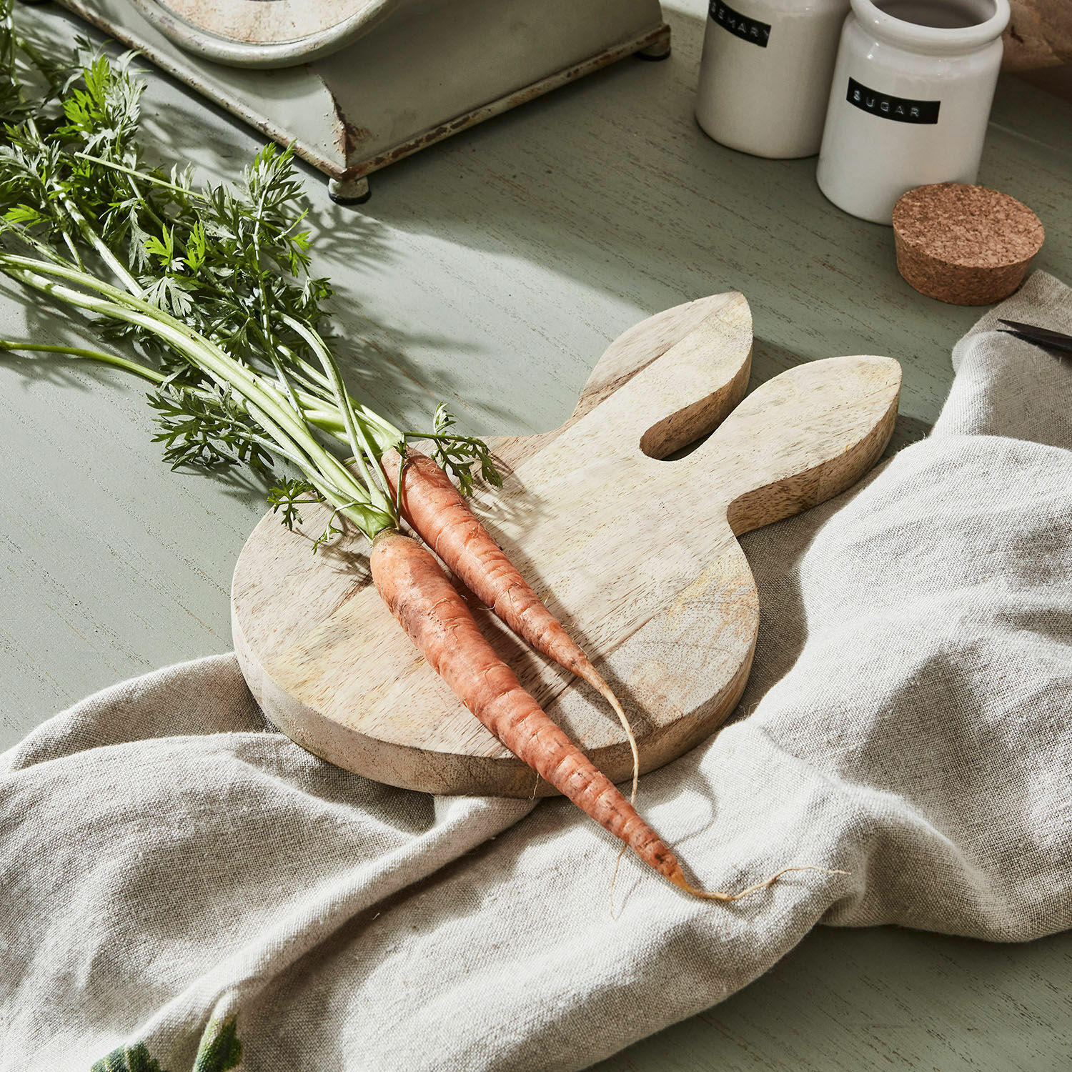 Tagliere Nante Tagliere in legno a forma di coniglio con due carote fresche su tessuto di lino
