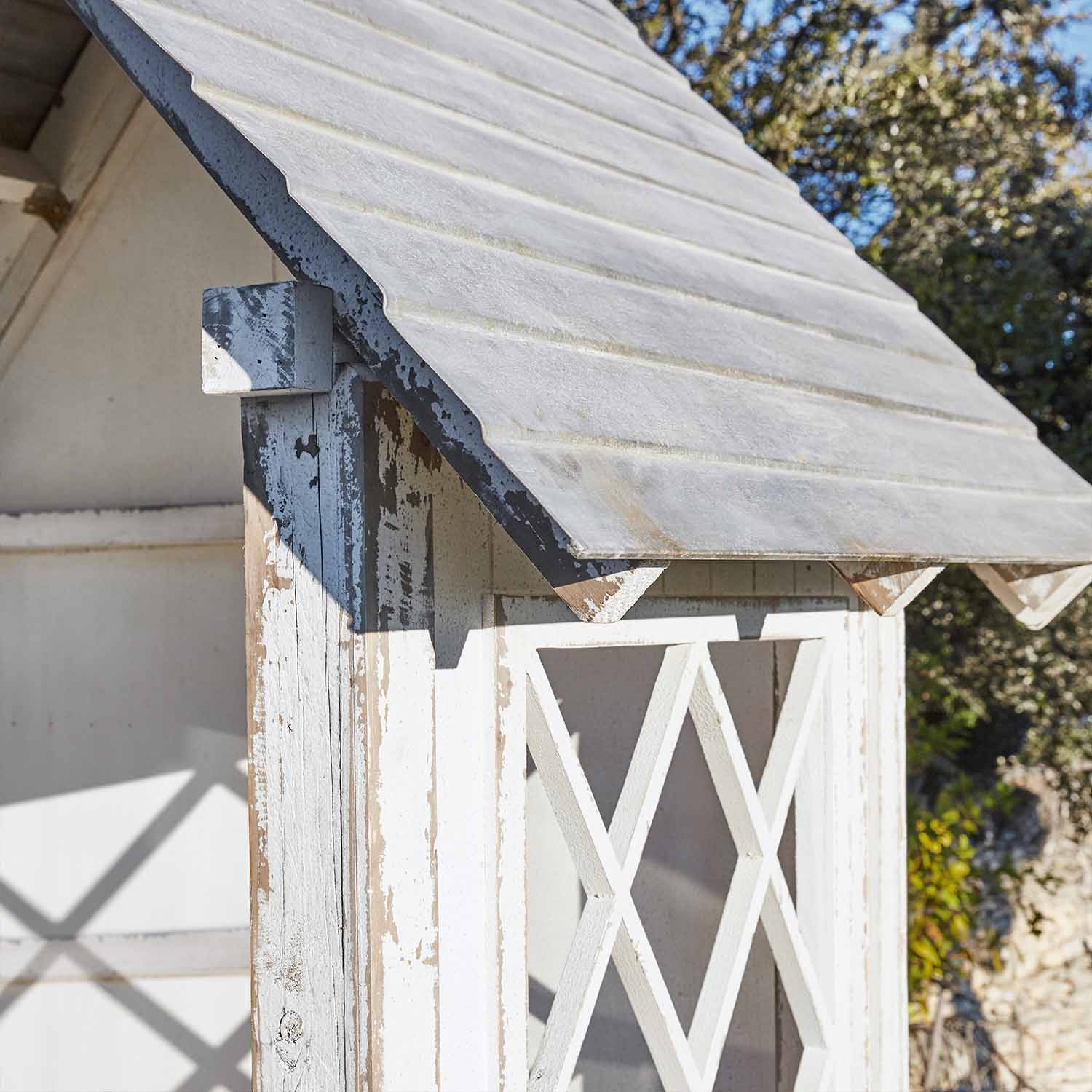Casetta da giardino in legno bianco con finitura usurata e tetto inclinato all'esterno