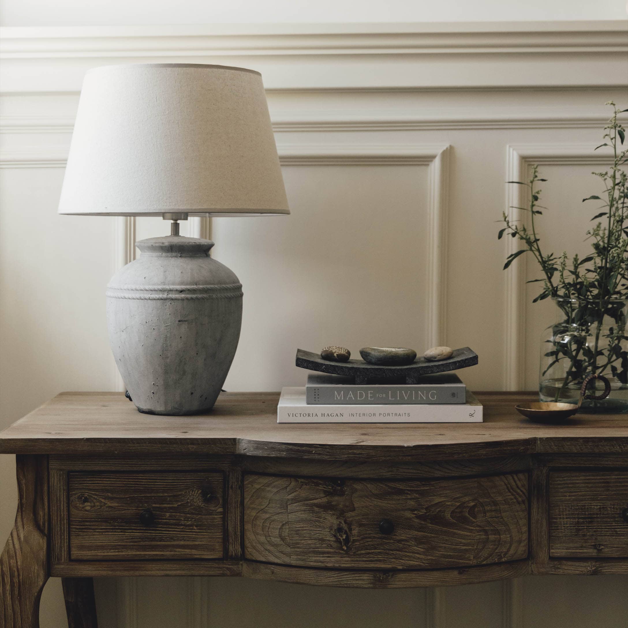 Lampada da tavolo in ceramica grigia con paralume beige su tavolo in legno rustico