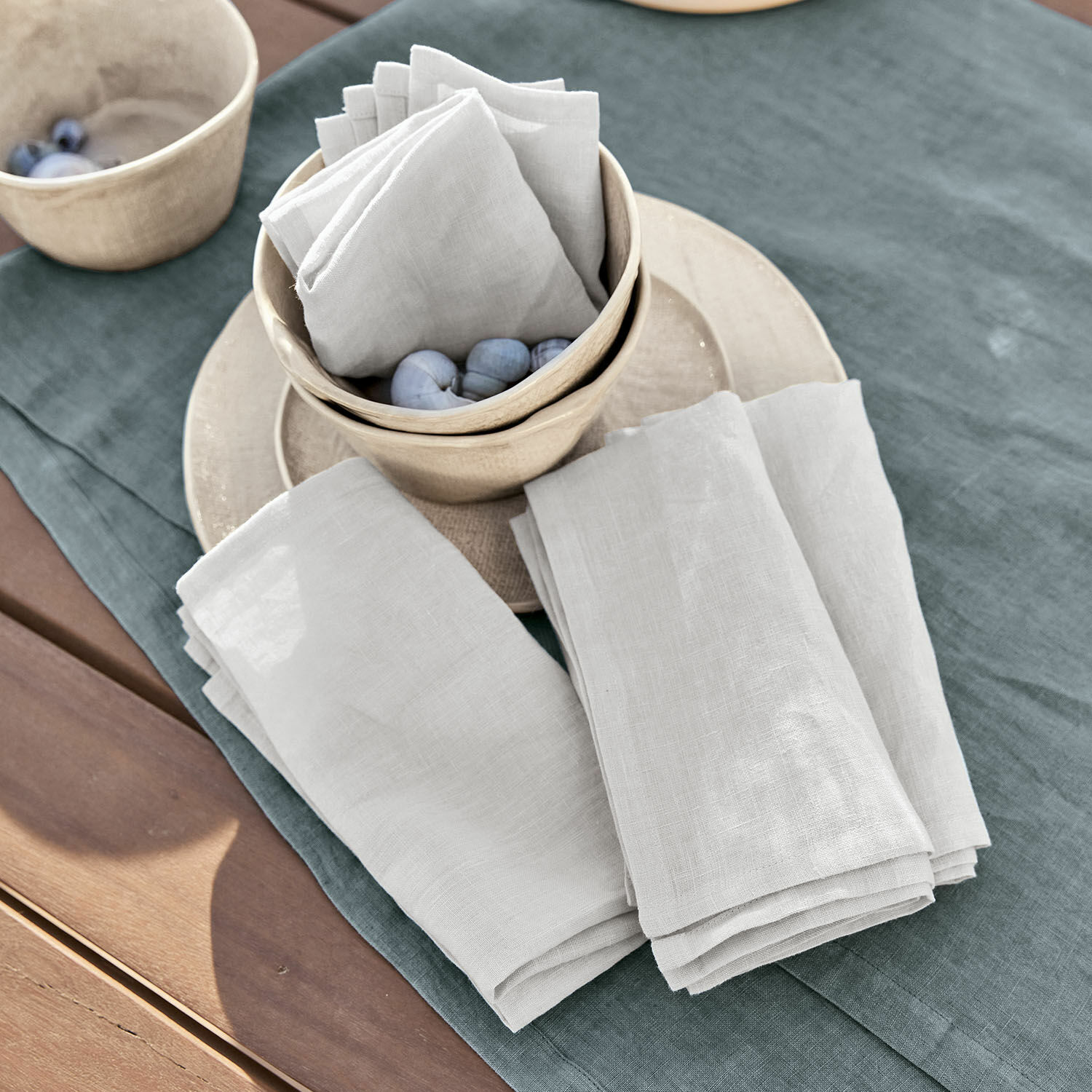 Set di 4 tovaglioli Ghis Tovaglioli in lino bianco su tovaglia verde con ciotole in ceramica e sfere decorative