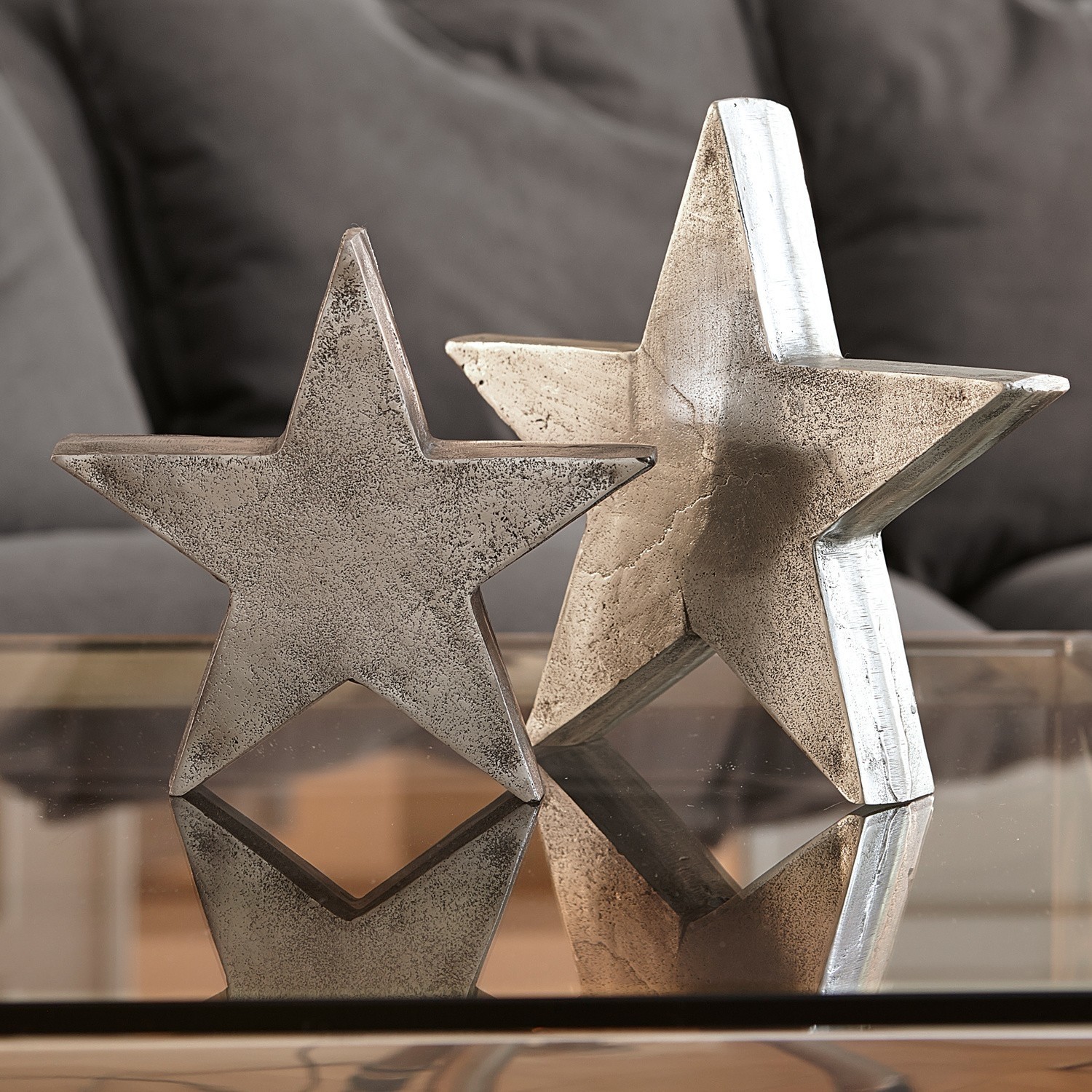 Coppia di stelle decorative Big Star Stelle decorative in metallo color argento su tavolo in vetro, ornamento per interni