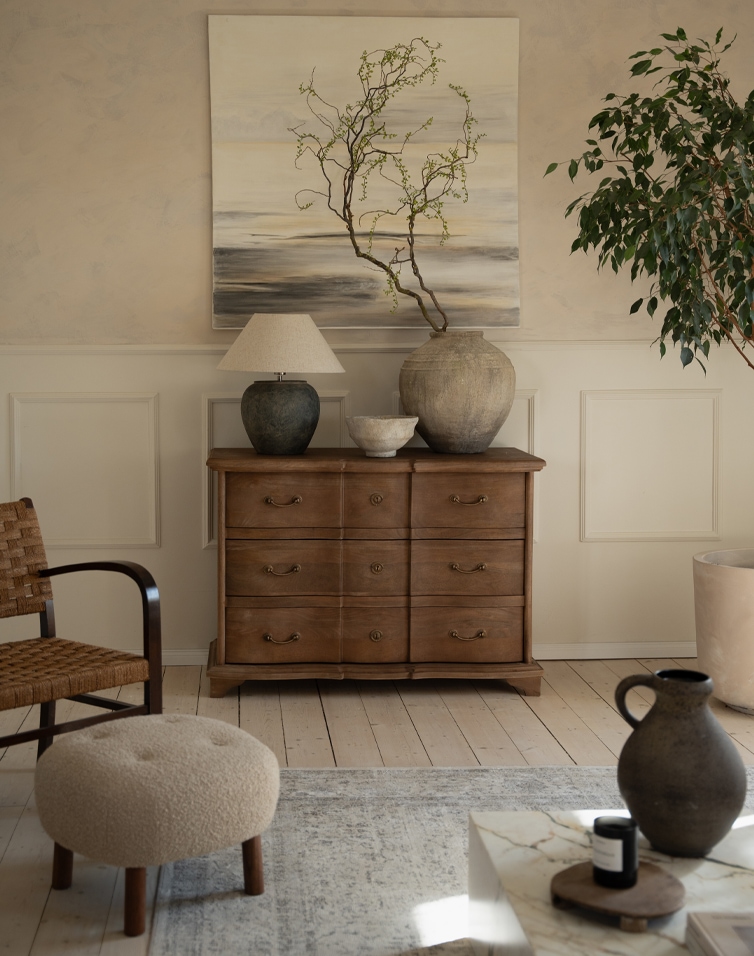 Comò in legno naturale con sei cassetti, vasi decorativi e lampada in soggiorno elegante