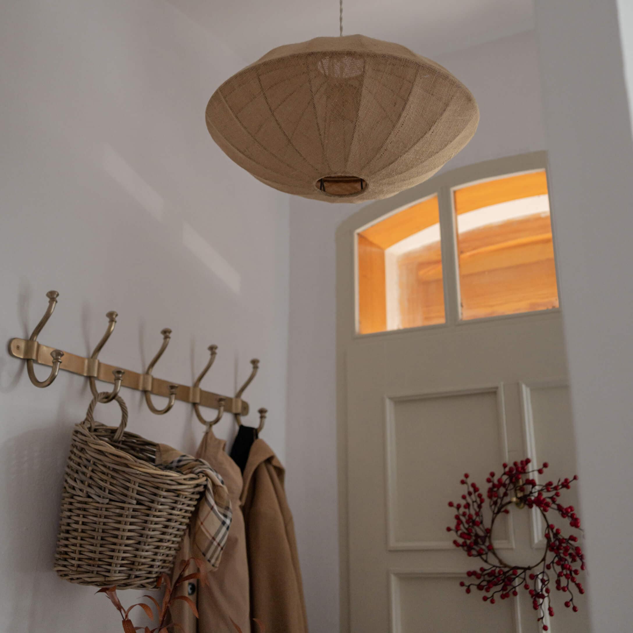 Lampada a sospensione beige in tessuto a forma di ampio paralume in ingresso con appendiabiti e cesta in vimini