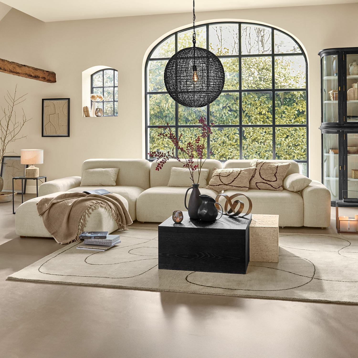 Divano Marnivelle Divano angolare beige con cuscini morbidi e tavolino nero in soggiorno moderno e luminoso