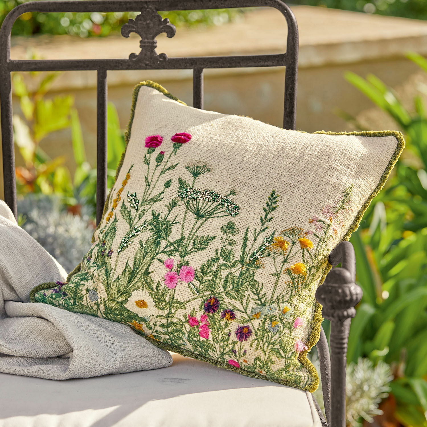 Copricuscino Aranno Cuscino in lino beige con ricamo floreale colorato e bordo verde su sedia da giardino in metallo