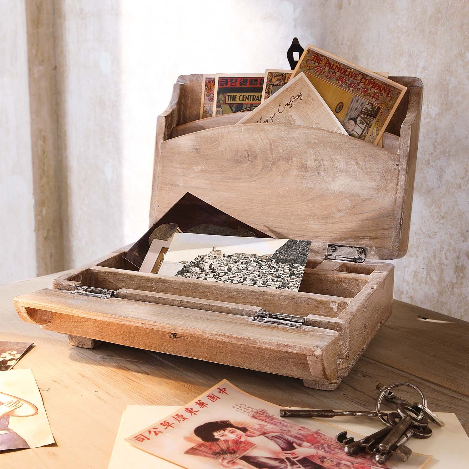 Scatola in legno naturale per lettere con cartoline vintage e chiavi metalliche su tavolo in legno