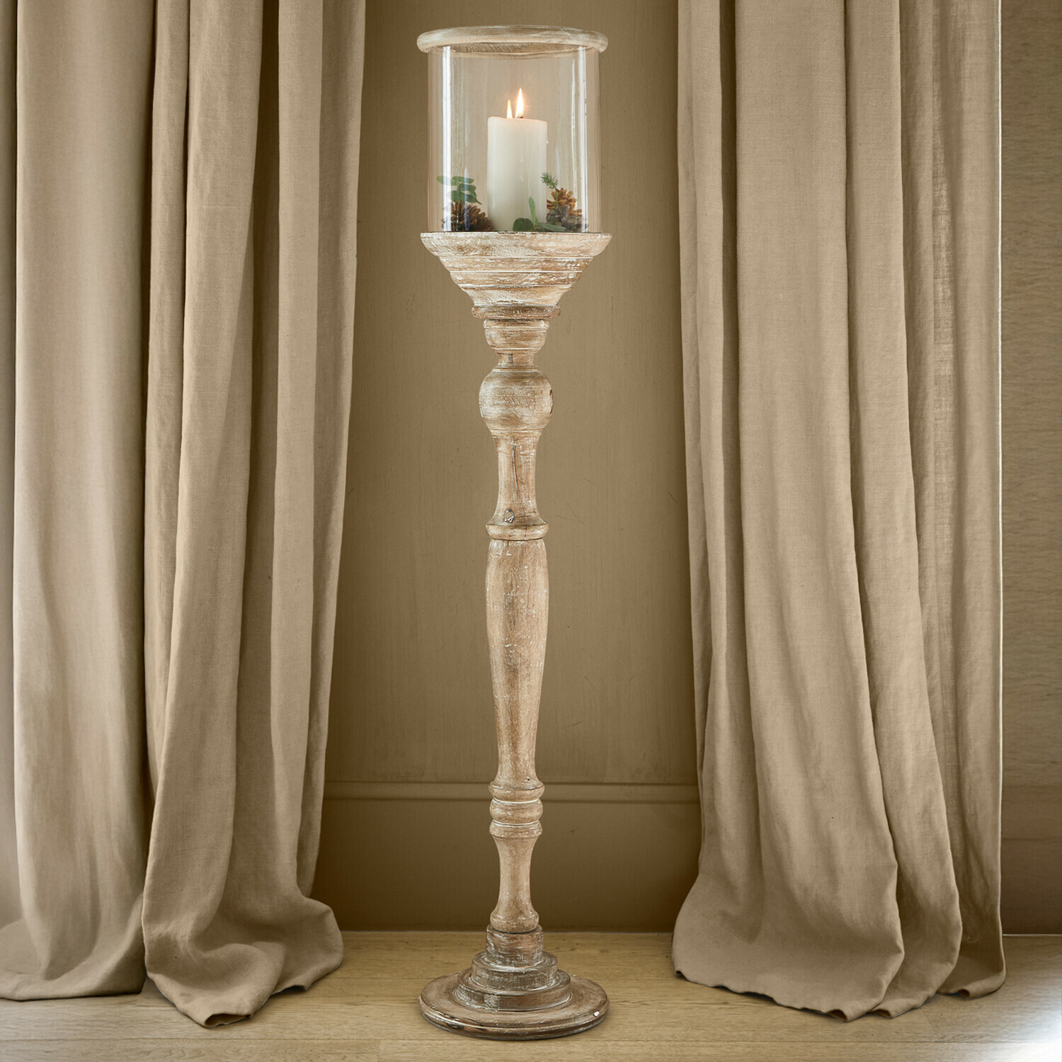 Candelabro Passion Poltrona in legno con cuscini verdi in ambiente luminoso e naturale con lanterna decorativa