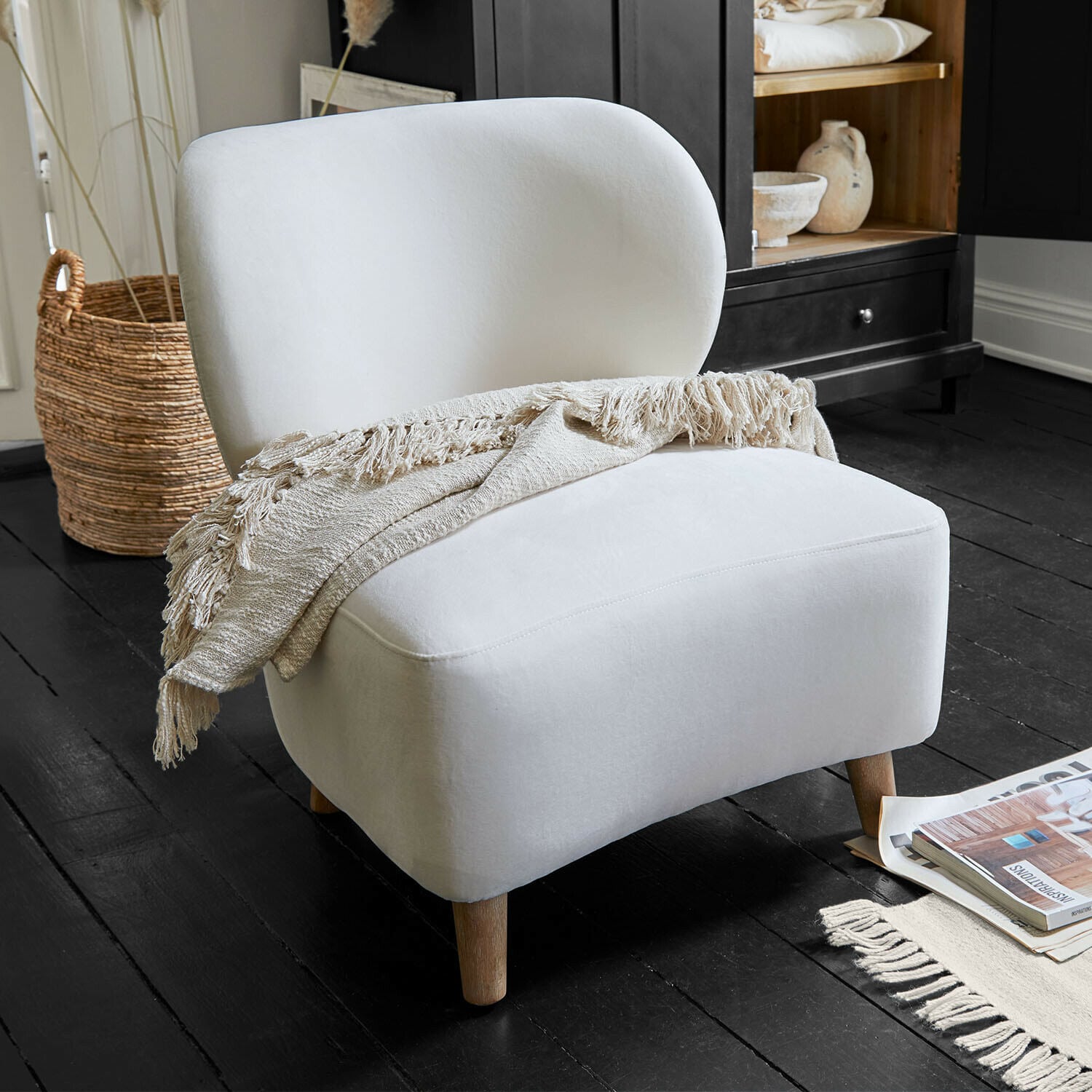 Poltrona Seraluna Poltrona imbottita bianca con gambe in legno e coperta beige su pavimento nero in soggiorno