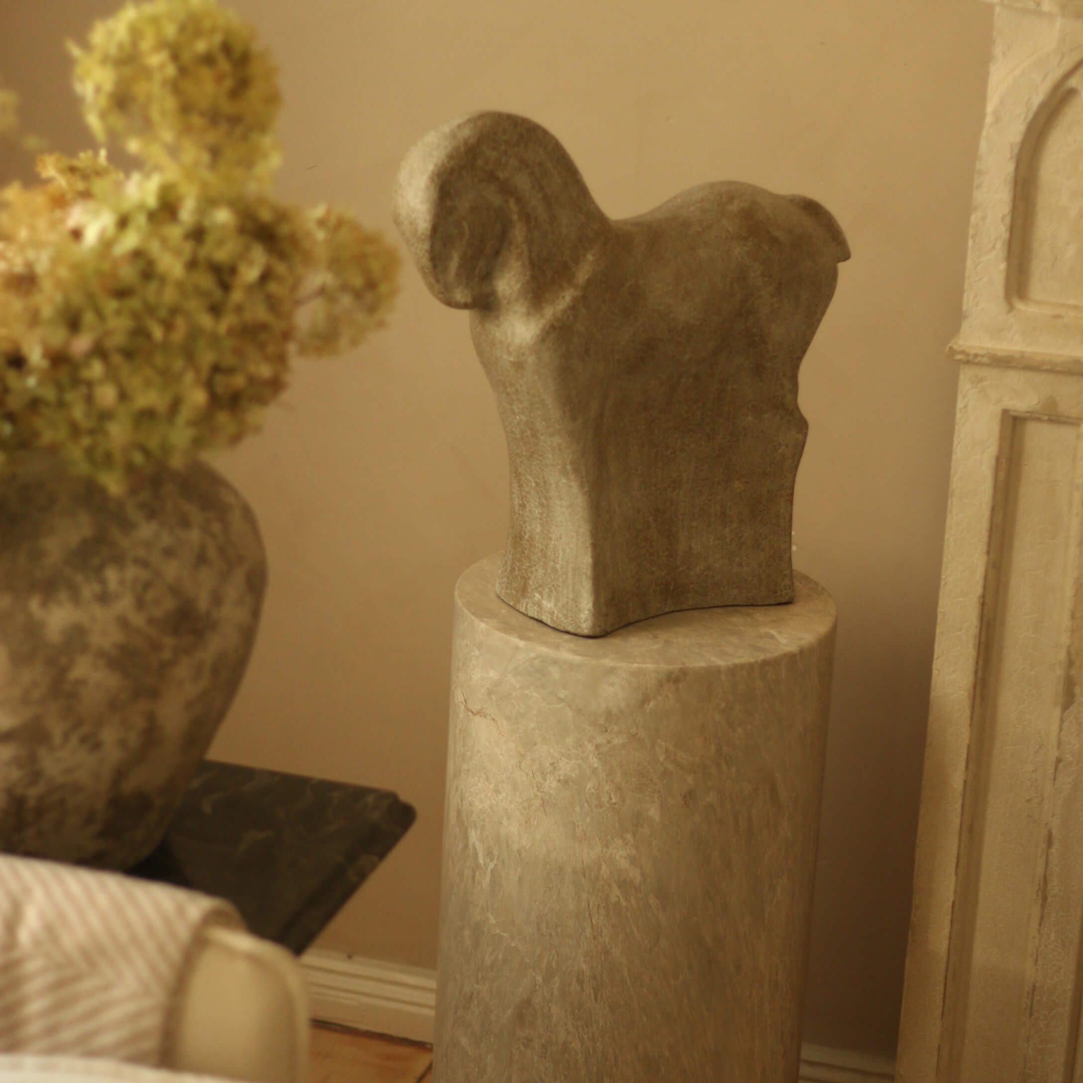 Scultura in pietra a forma di animale su piedistallo in marmo in ambiente caldo
