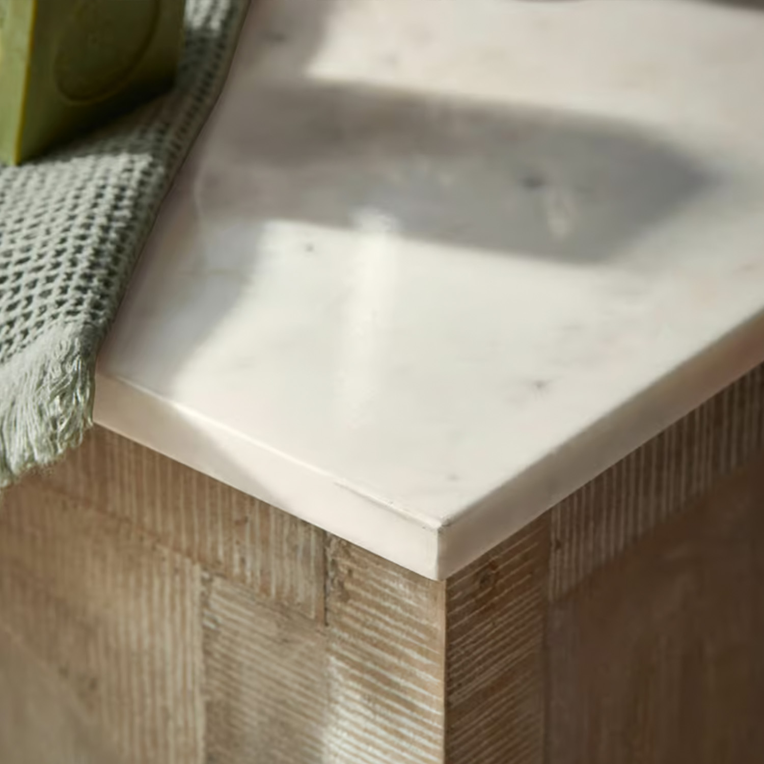 Piano in marmo bianco su base in legno con asciugamano verde in tessuto, mobile moderno
